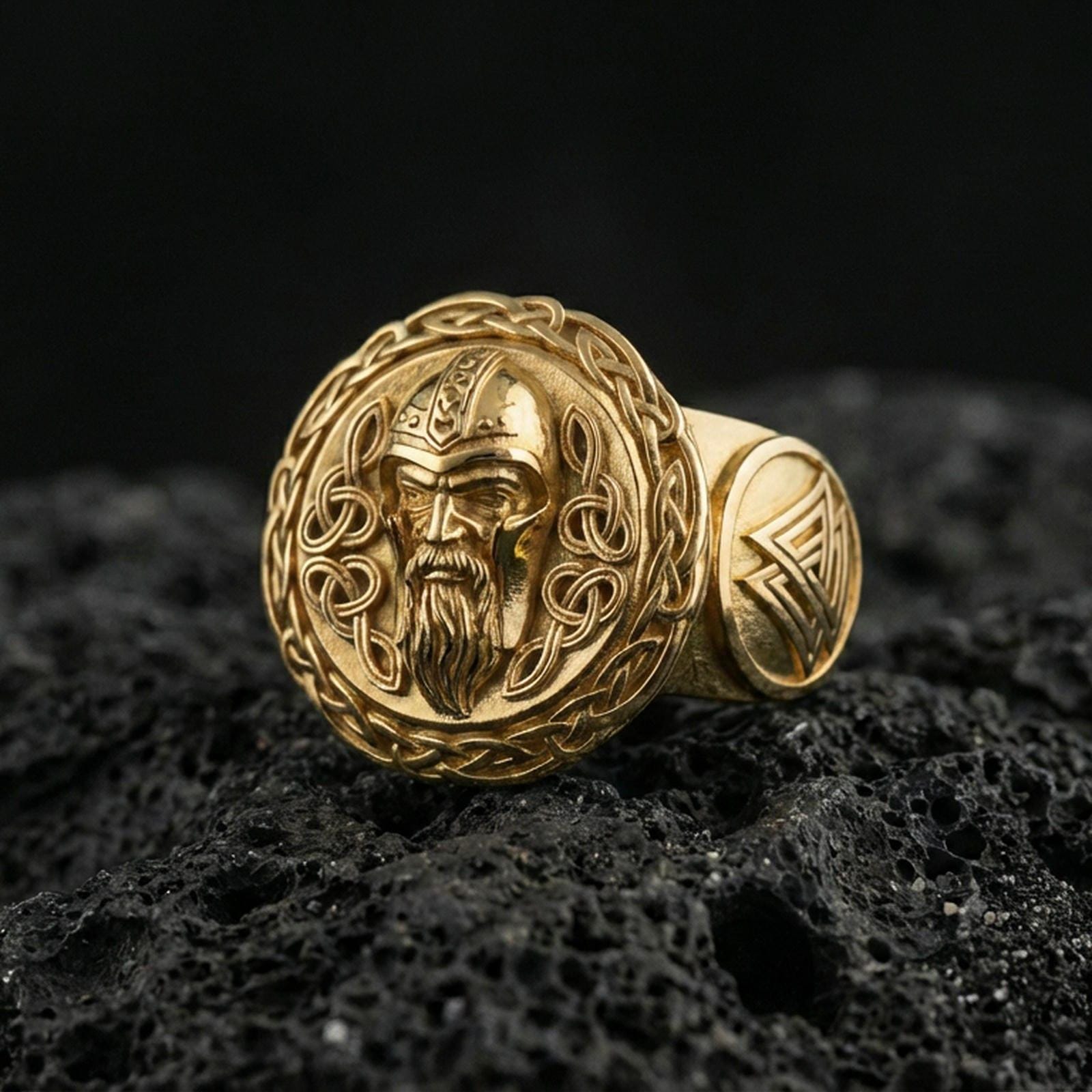 Odin the All-Father ring in a gold plated finish on volcanic rock, Valhalla Viking portrait design with rune-style accents, premium macro product image