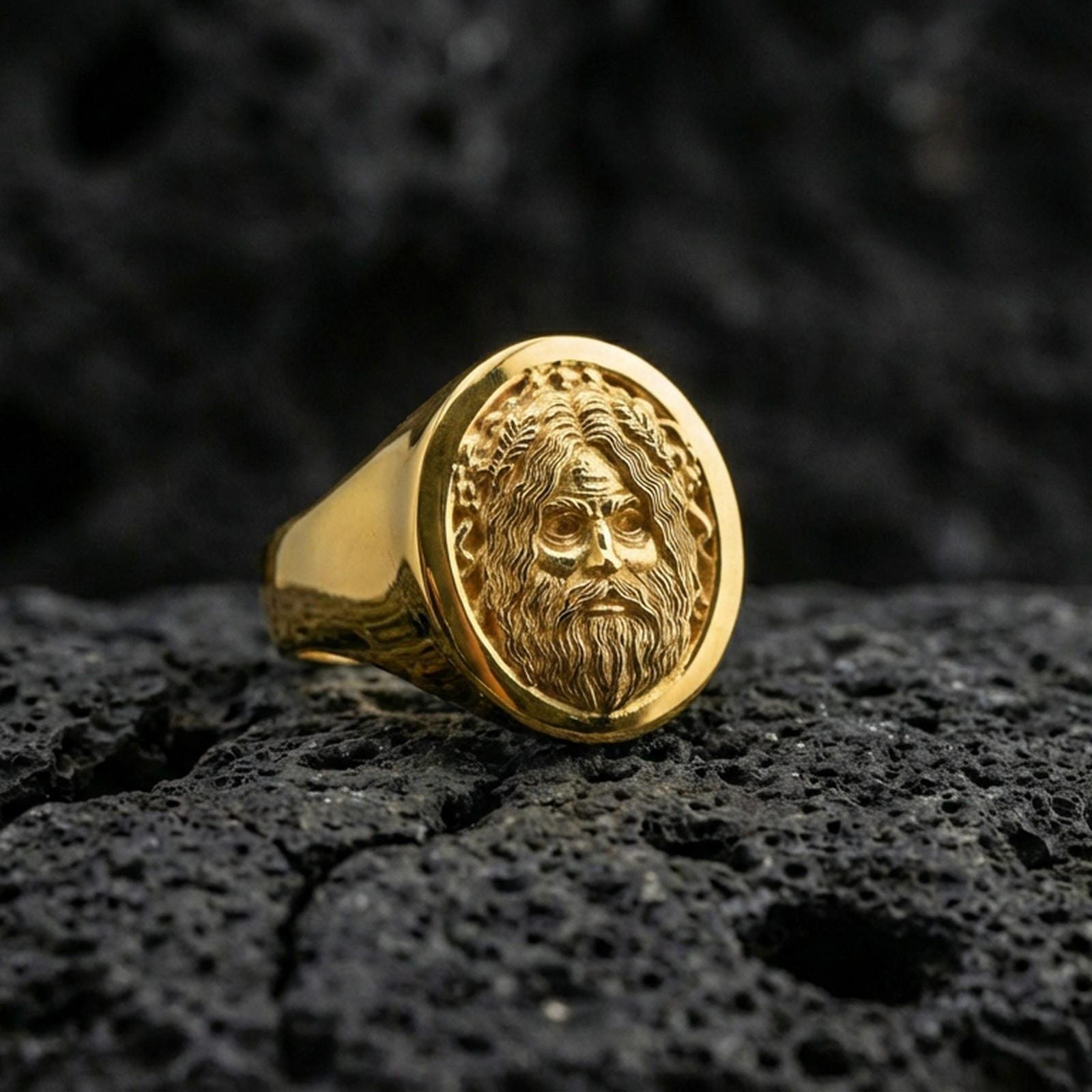 Oval Odin Viking signet ring in a gold plated finish on volcanic rock, Norse god portrait design, premium macro product image
