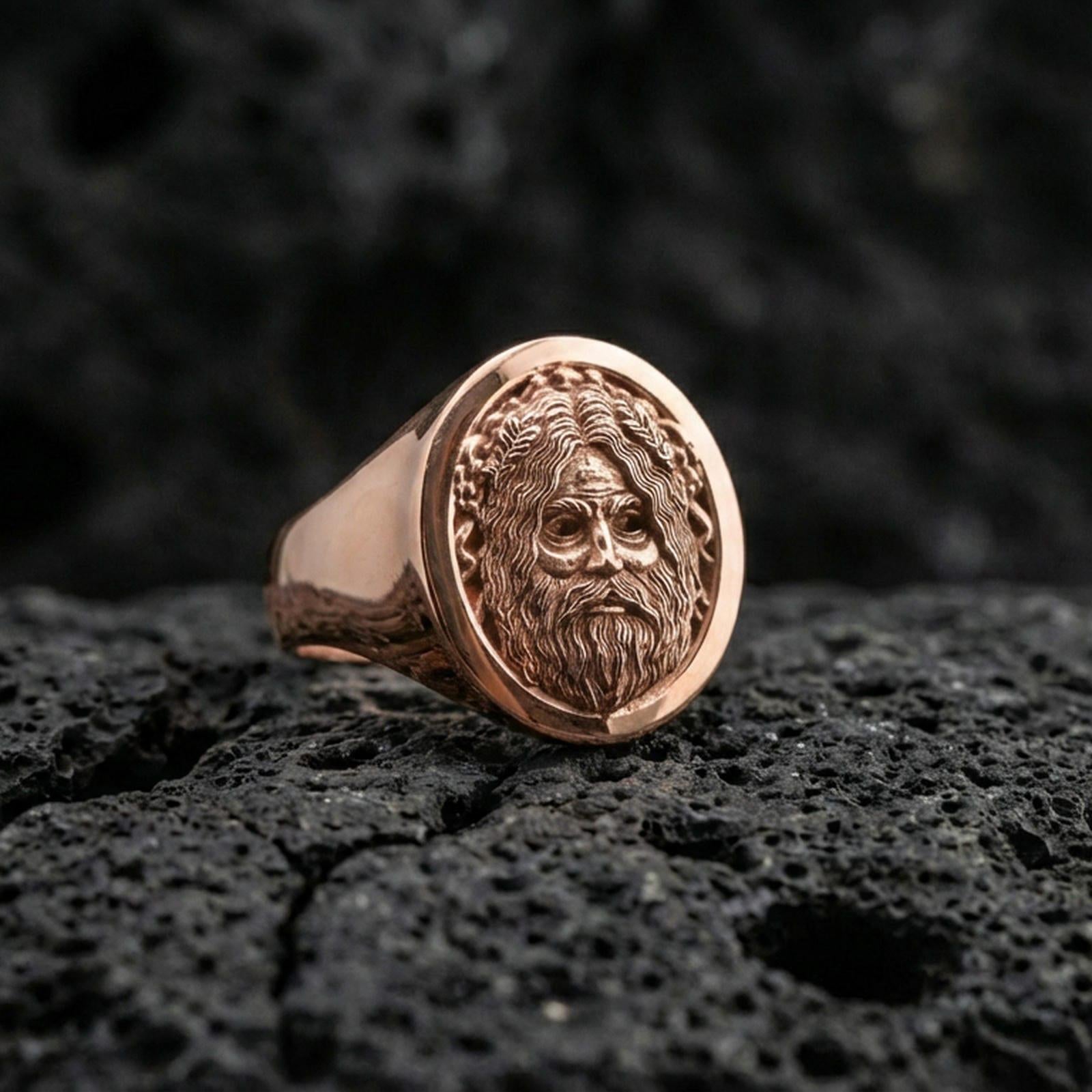 Oval Odin Norse mythology signet ring in a rose gold plated finish on volcanic rock, detailed Odin face engraving, luxury studio close-up