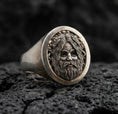 Load image into Gallery viewer, Oval Odin Norse god signet ring in an oxidized sterling silver finish on volcanic rock, detailed bearded portrait engraving, macro studio product shot
