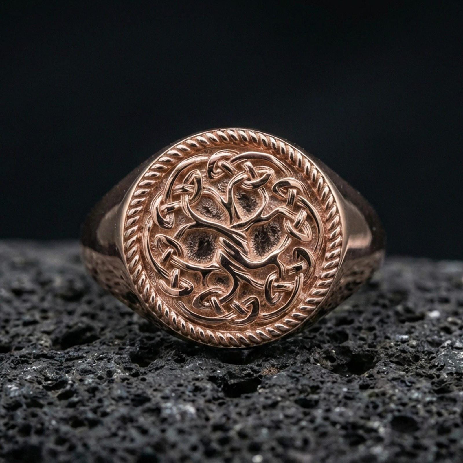 Yggdrasil ring in a rose gold plated finish on volcanic rock, ornate Norse Tree of Life knot pattern, luxury studio close-up
