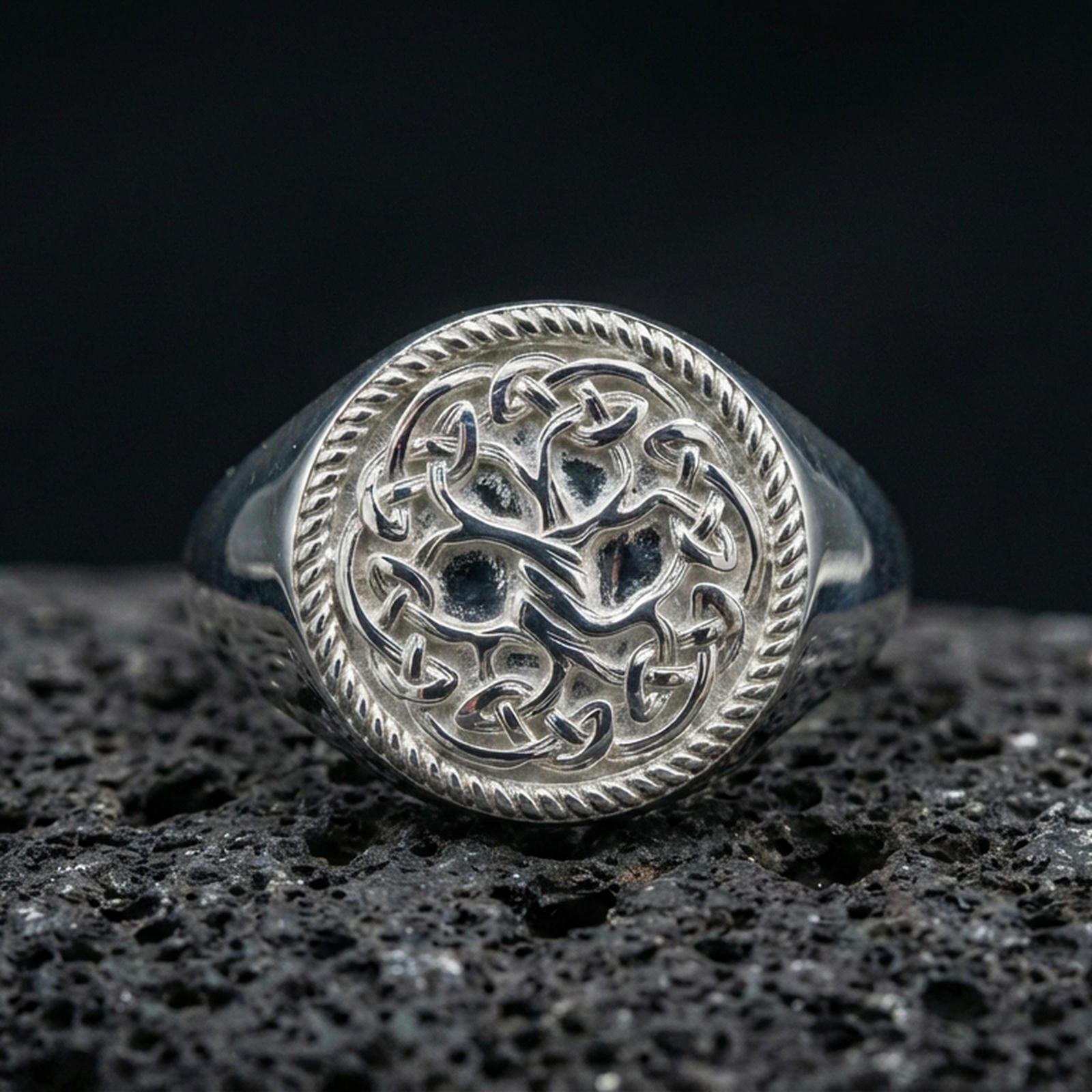 Sterling silver Yggdrasil ring in polished silver finish on volcanic rock, Norse Tree of Life motif with braided frame, close-up photo