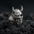 Load image into Gallery viewer, Sterling silver undead oni mask ring in an oxidized finish on volcanic rock, Japanese yokai demon face with horns, macro studio product shot
