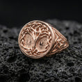 Load image into Gallery viewer, Norse Tree of Life ring in a rose gold plated finish on volcanic rock, Celtic knot band with Yggdrasil engraving, luxury studio close-up
