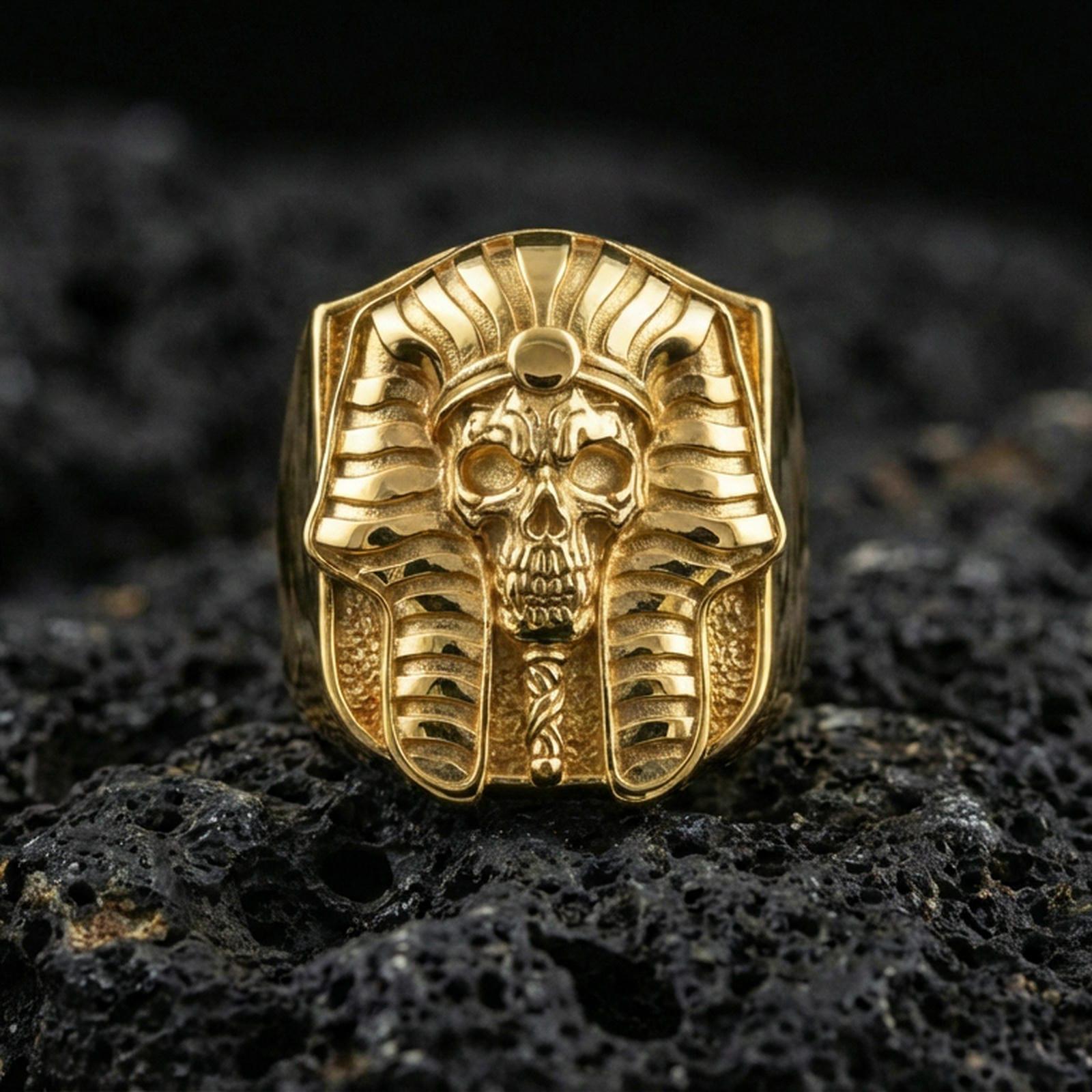 Pharaoh skull ring in a gold plated finish on volcanic rock, ancient Egyptian memento mori statement design, premium macro product image