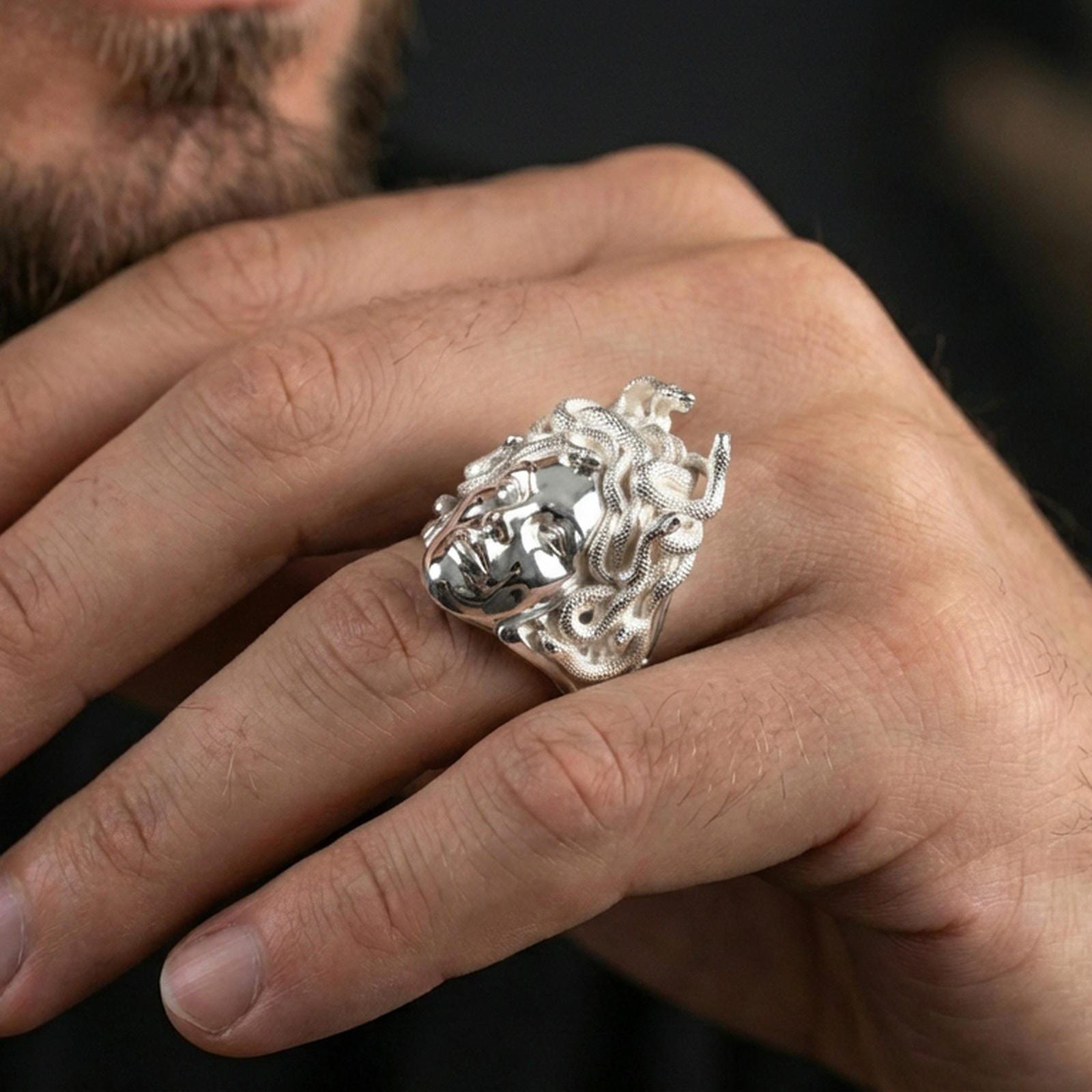 Medusa ring in polished silver finish on finger, Greek mythology gorgon face design, natural lifestyle wear shot