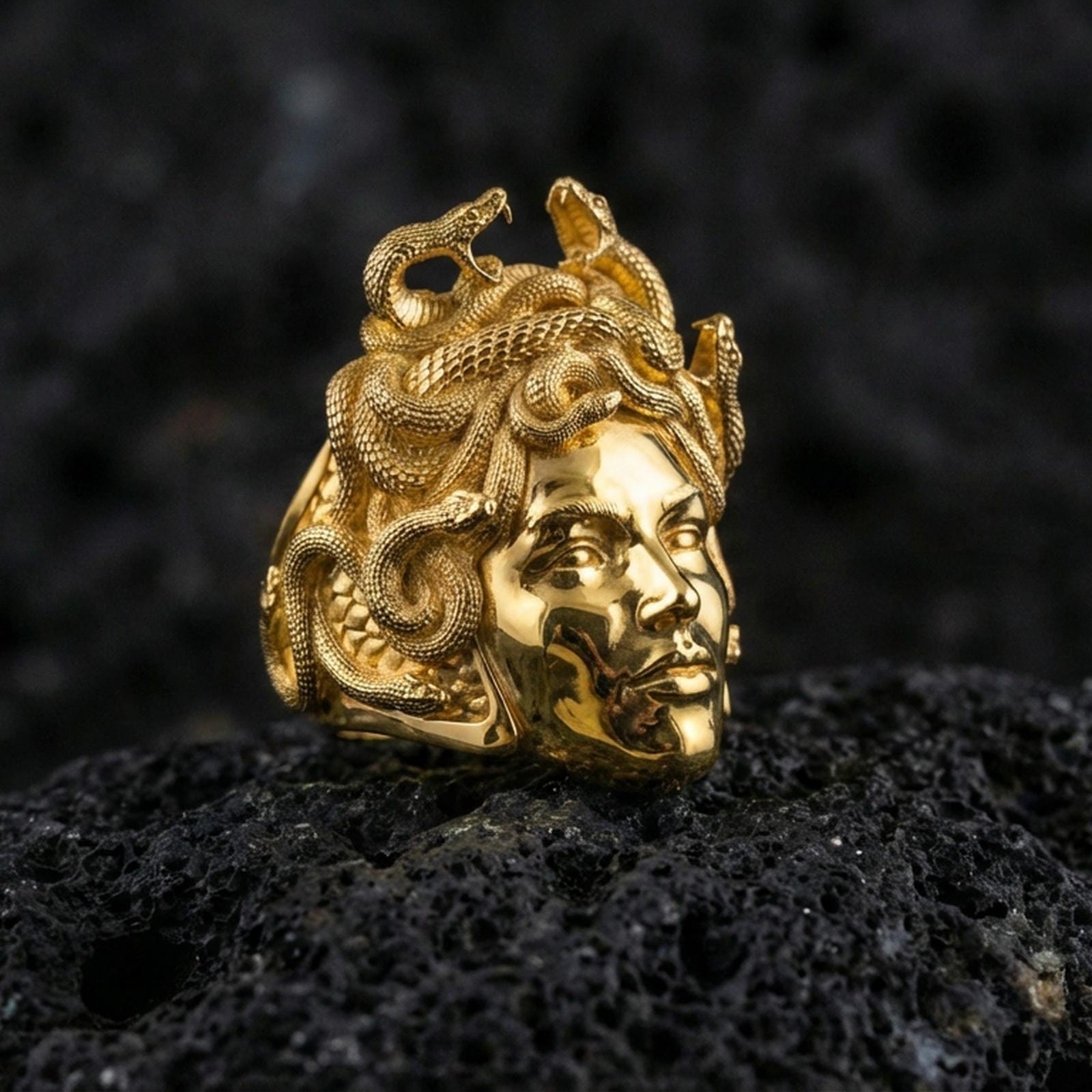 Medusa gorgon ring in a gold plated finish on volcanic rock, bold snake hair goddess statement design, premium macro product image