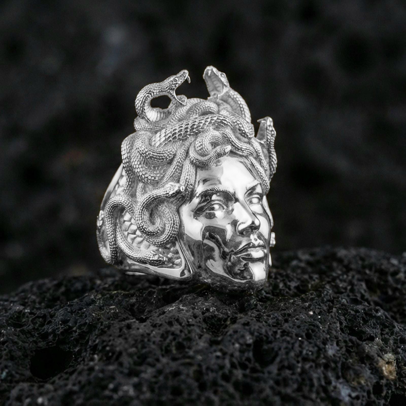 Sterling silver Medusa ring in polished silver finish on volcanic rock, Greek mythology gorgon face with coiled snakes, close-up product photo