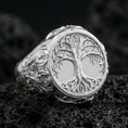 Load image into Gallery viewer, Yggdrasil ring in polished silver finish on volcanic rock, detailed tree of life engraving with ornamental side scrollwork, premium close-up product photo
