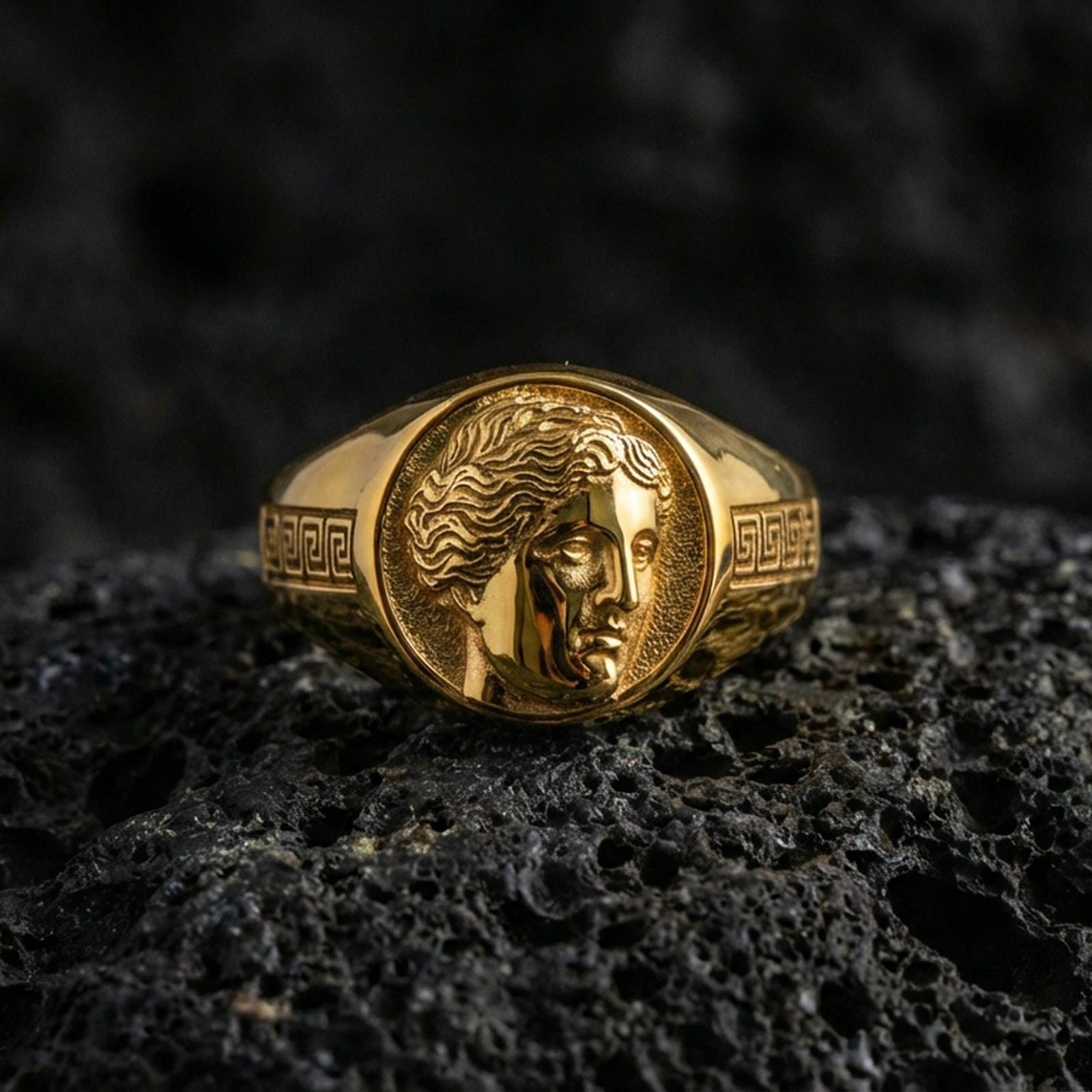 Venus goddess signet ring in a gold plated finish on volcanic rock, antique Roman cameo relief with Greek key detail, luxury macro product photo