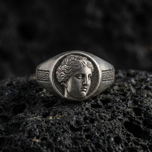 Sterling silver Venus goddess signet ring in an oxidized finish on volcanic rock, Roman profile portrait with Greek key sides, macro jewelry shot