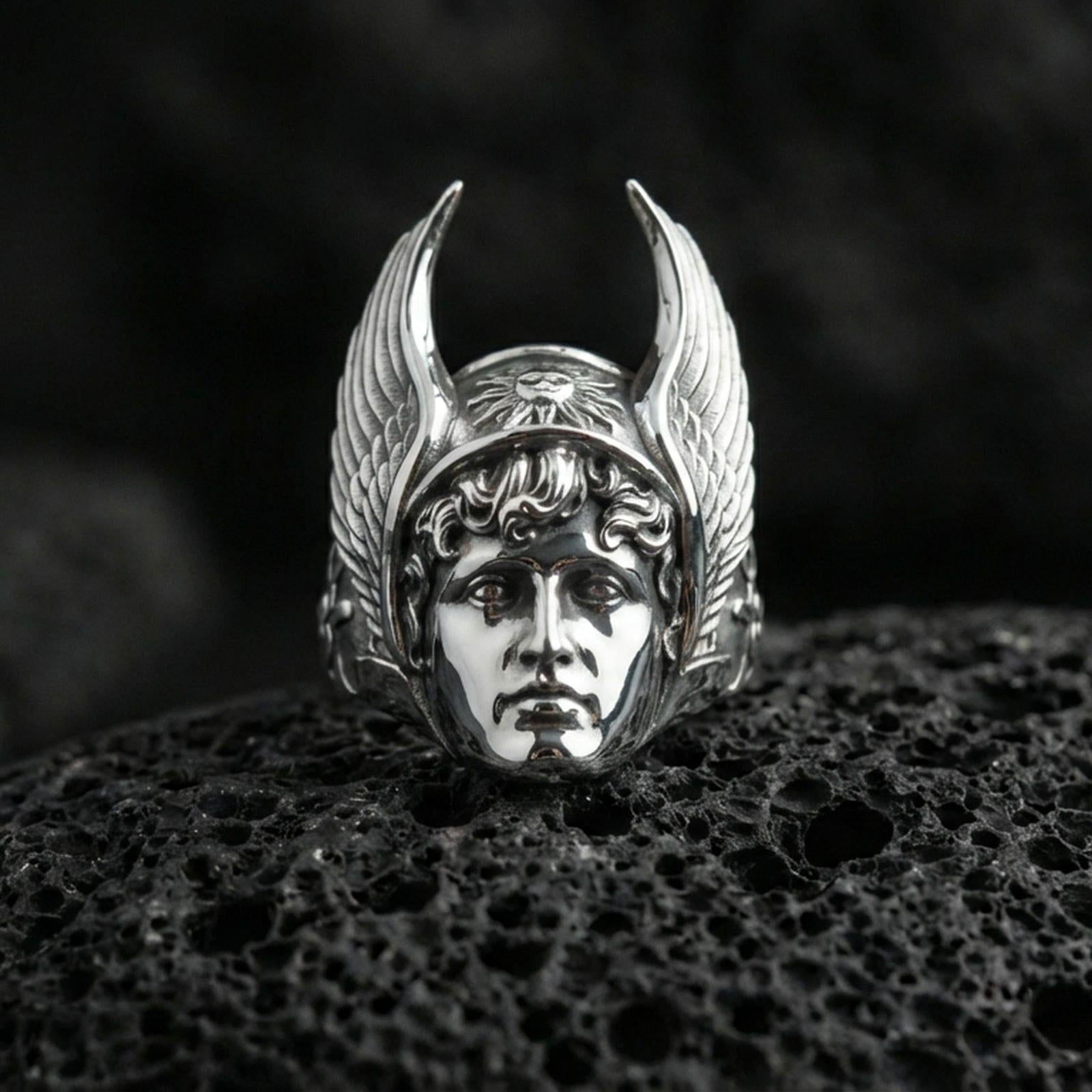 Hermes winged helmet ring in polished silver finish on volcanic rock, highly reflective god portrait with detailed feathers, premium close-up
