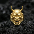 Load image into Gallery viewer, Japanese Hannya mask ring in a gold plated finish on volcanic rock, dramatic demon face carving with horns and teeth, luxury macro shot
