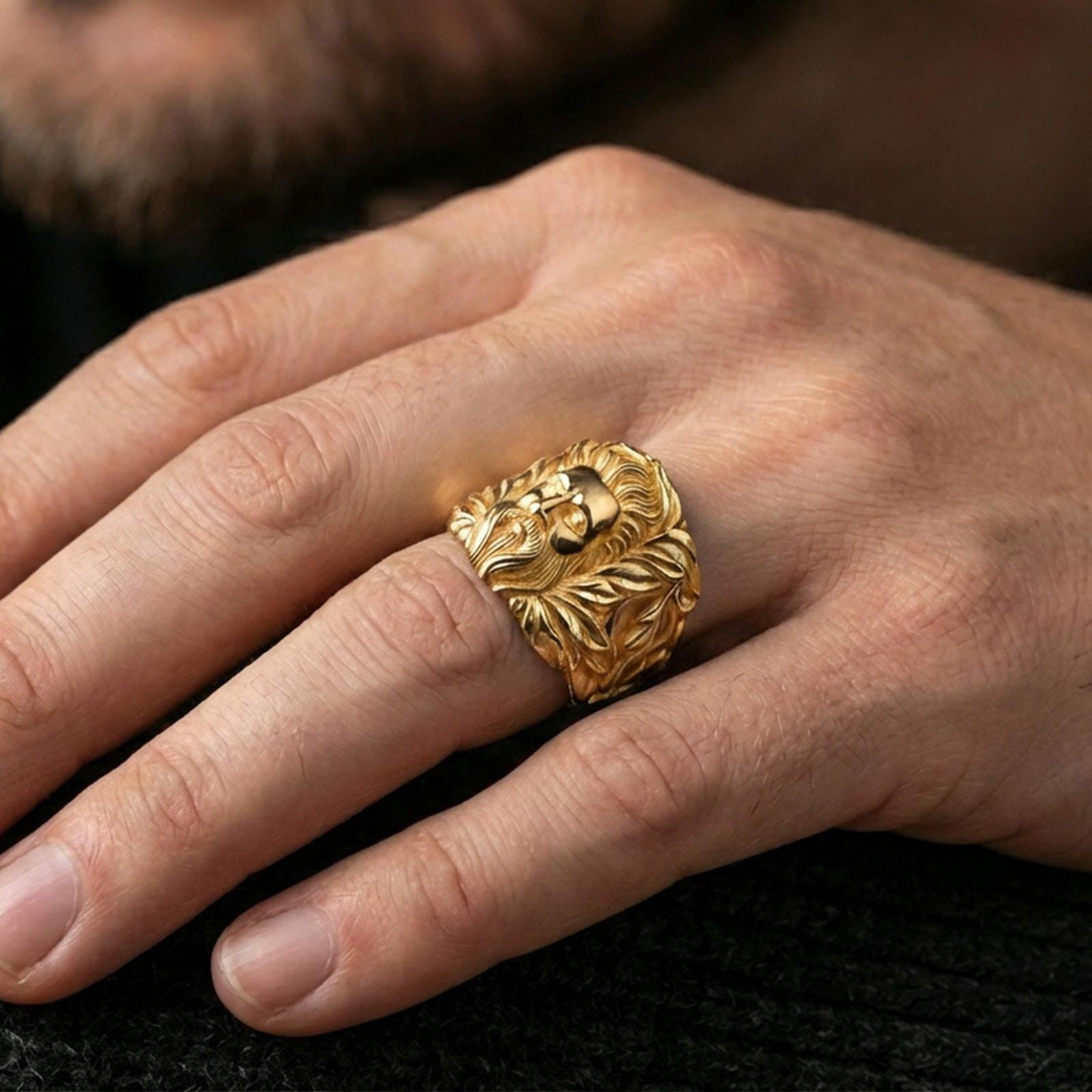 Gold plated statement ring worn on finger, classical bearded figure centerpiece with engraved leaves, premium lifestyle close-up