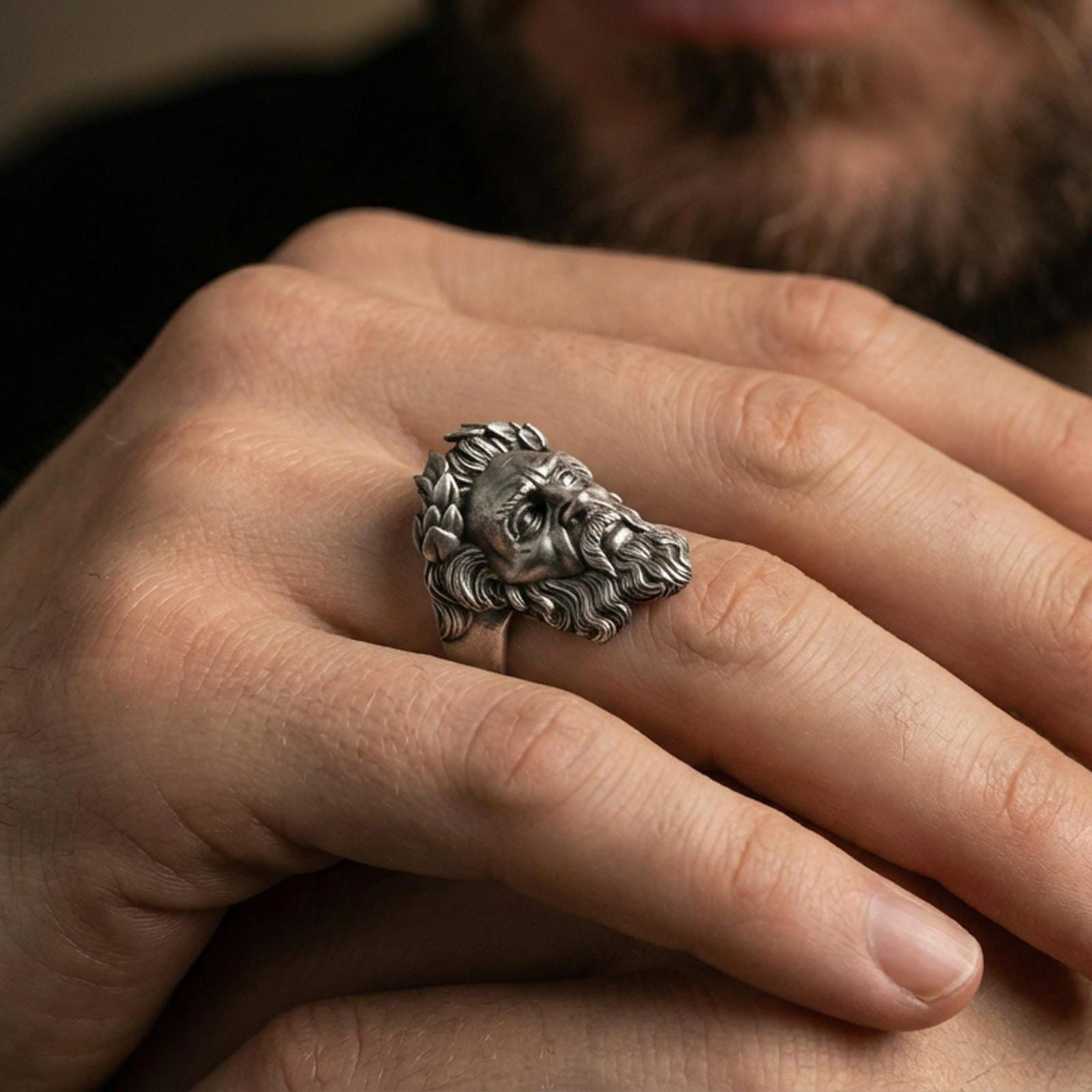 Oxidized sterling silver Zeus ring worn on finger, bold Greek mythology design with laurel wreath crown, masculine lifestyle hand shot