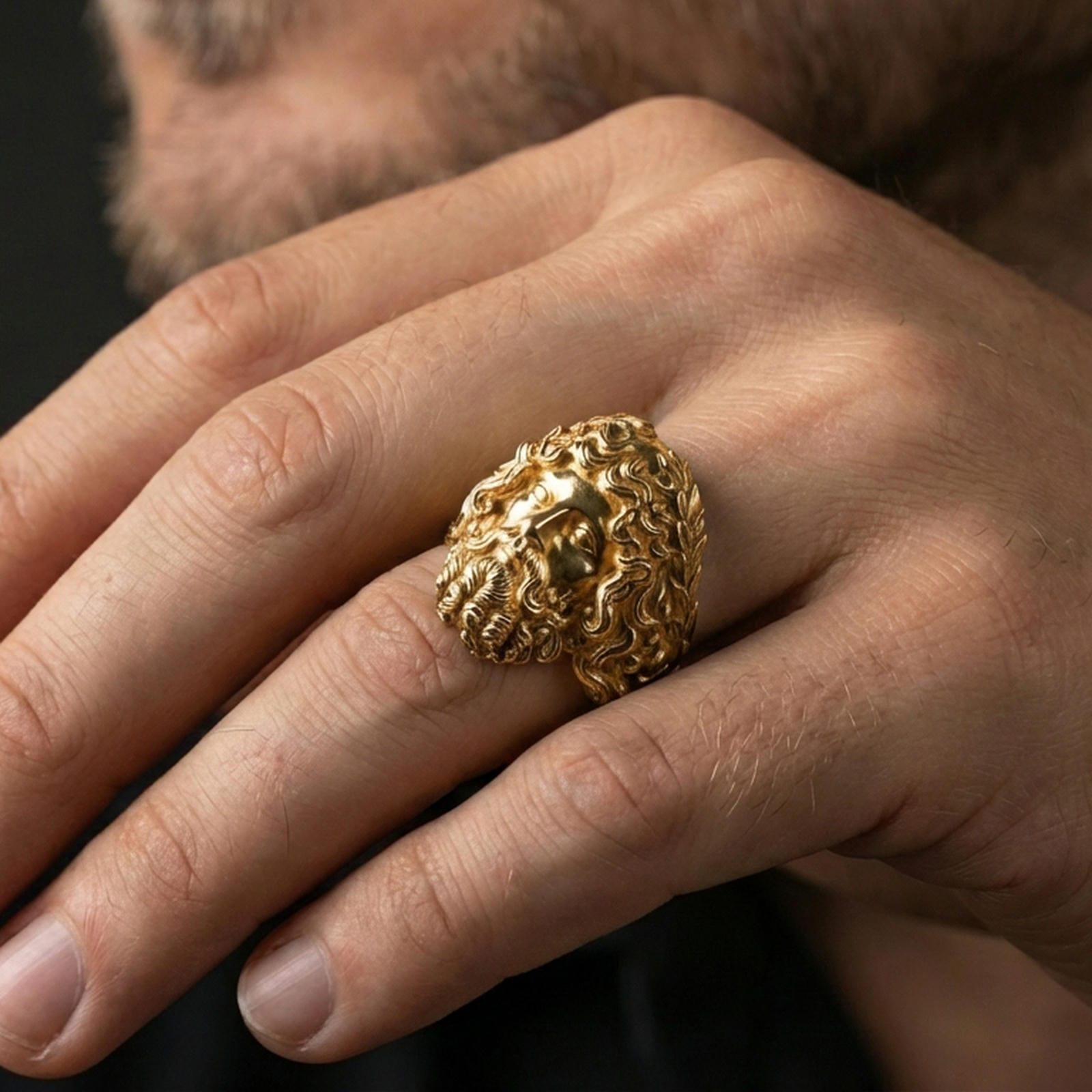 Gold plated Zeus signet ring worn on finger, statement mythology jewelry with powerful god head motif, premium lifestyle close-up