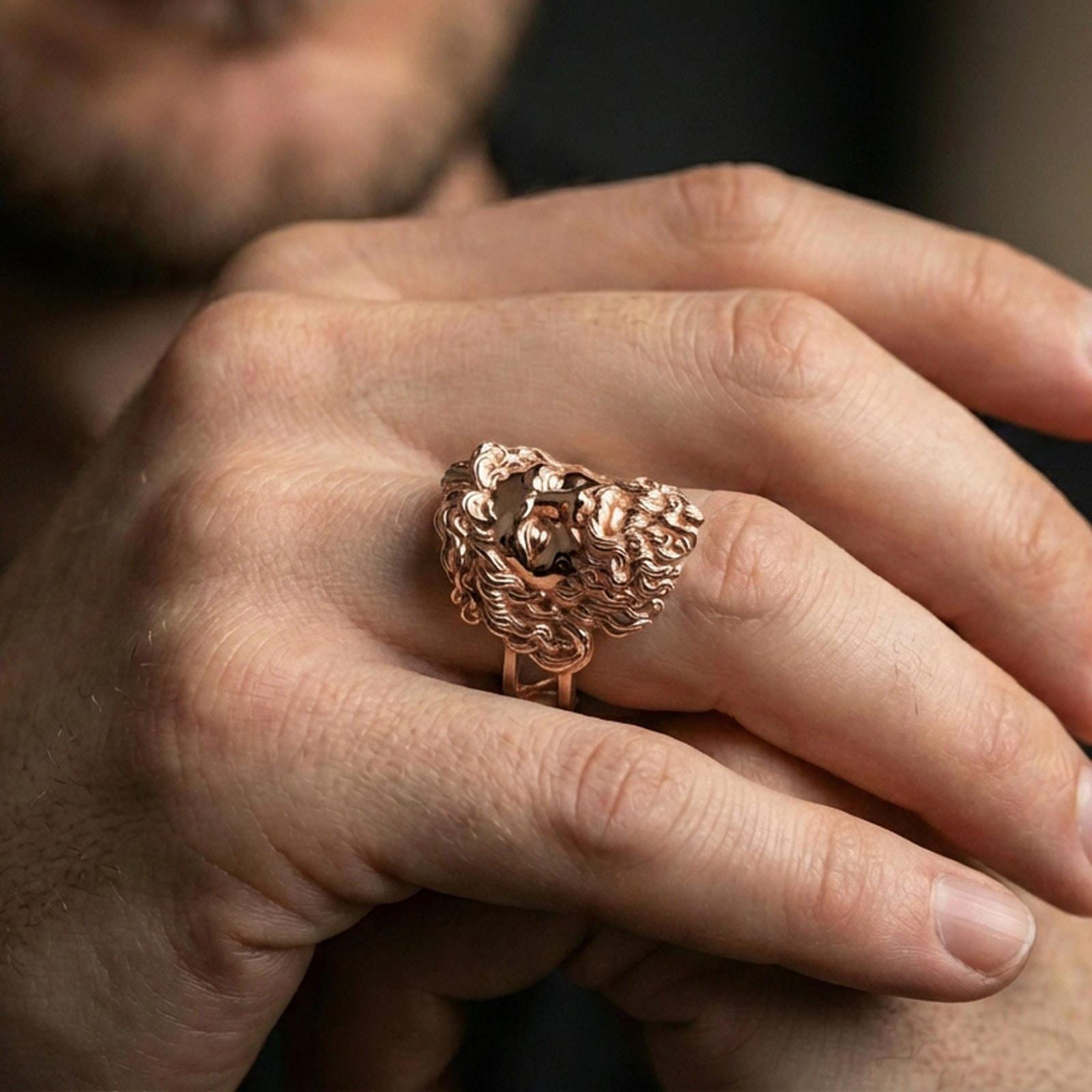 Rose gold plated Zeus ring on finger featuring ornate sculpted face, refined lifestyle jewelry wear shot