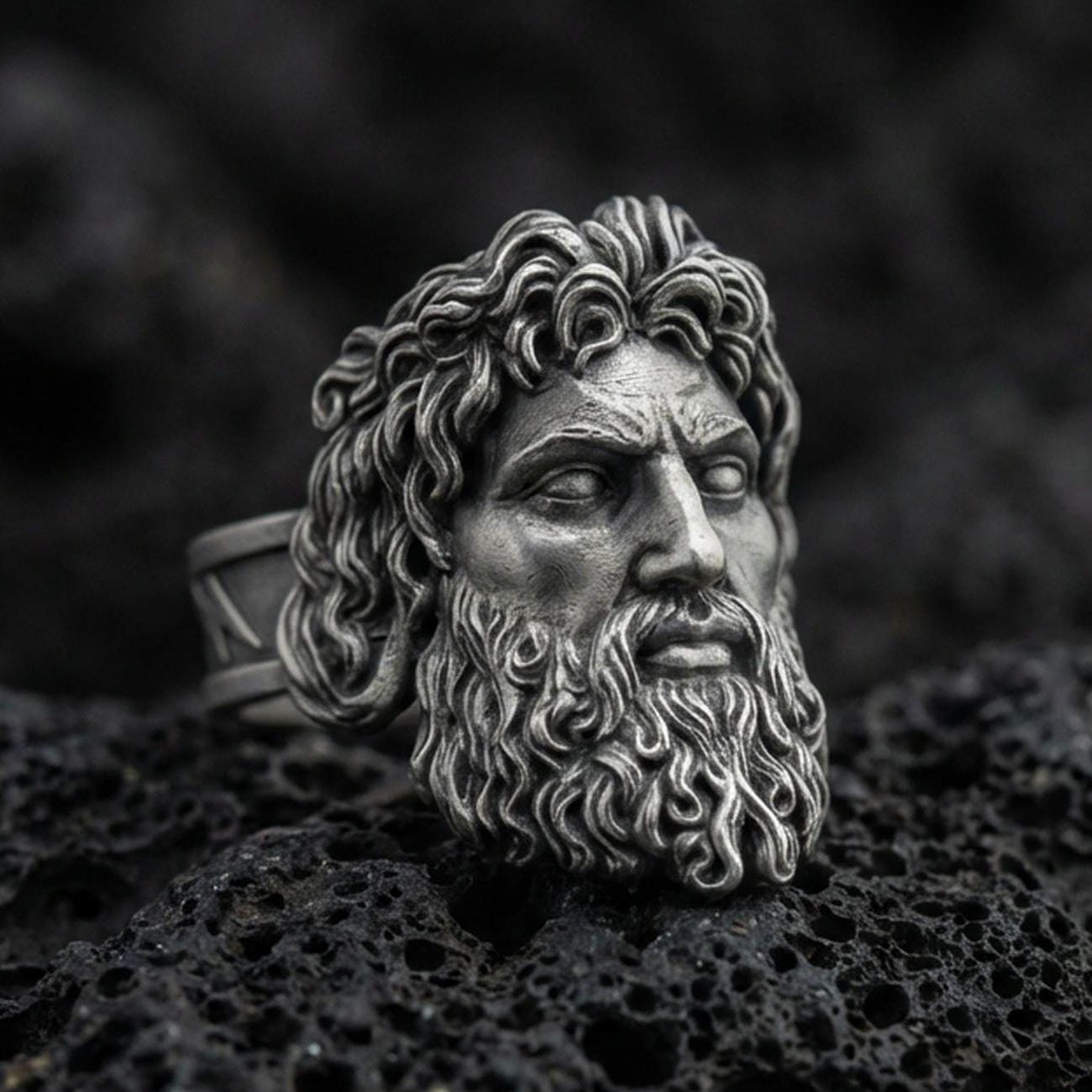 Detailed Zeus signet ring crafted in oxidized sterling silver, intense Greek god facial expression, macro product shot on textured volcanic rock background