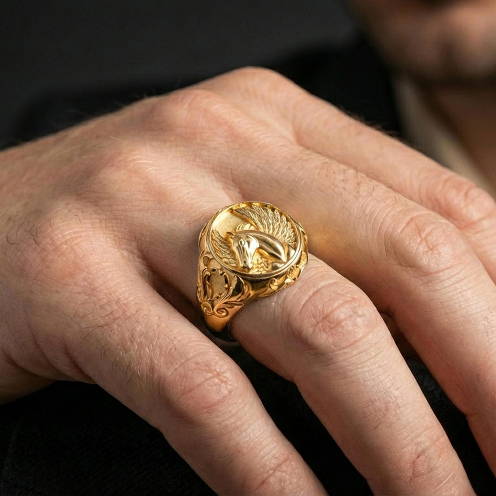 Gold plated Pegasus signet ring worn on finger, statement fantasy jewelry inspired by mythical winged horse, premium lifestyle close-up