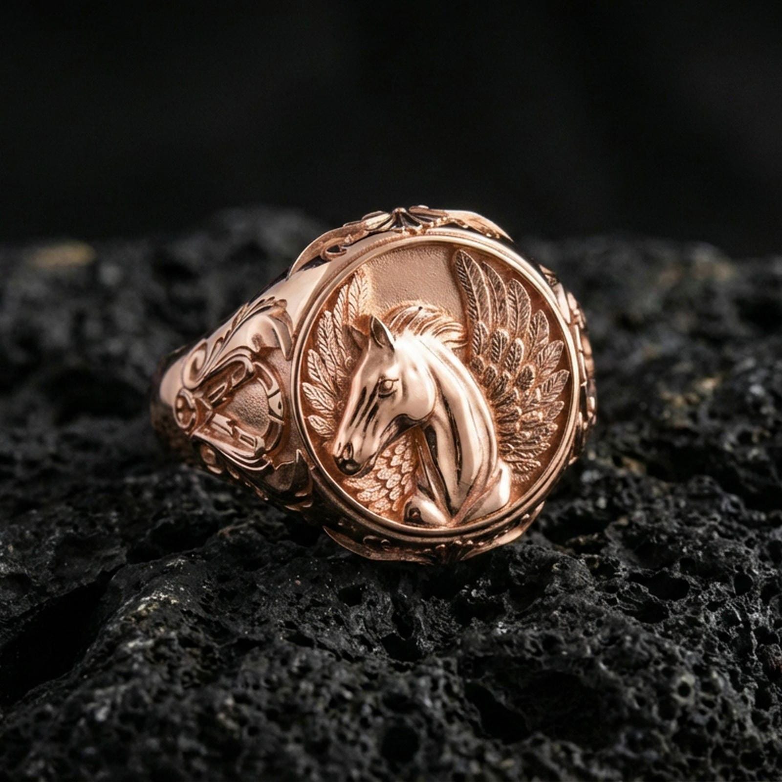 Rose gold plated Pegasus ring showcasing elegant winged horse motif and refined engraving, sharp close-up product photography on volcanic rock