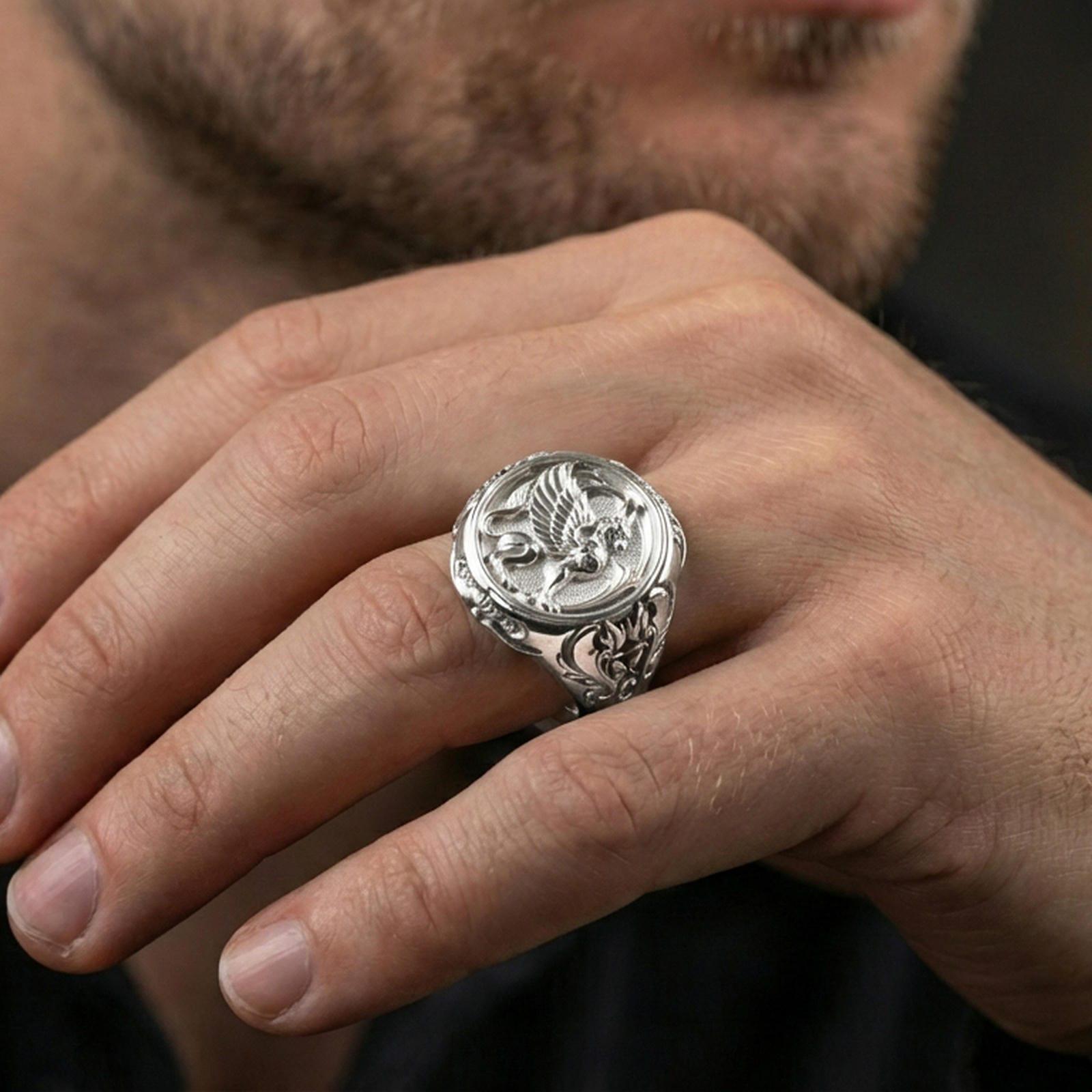 Polished silver griffon ring on finger highlighting detailed griffin relief and ornamental frame, clean lifestyle wear photo