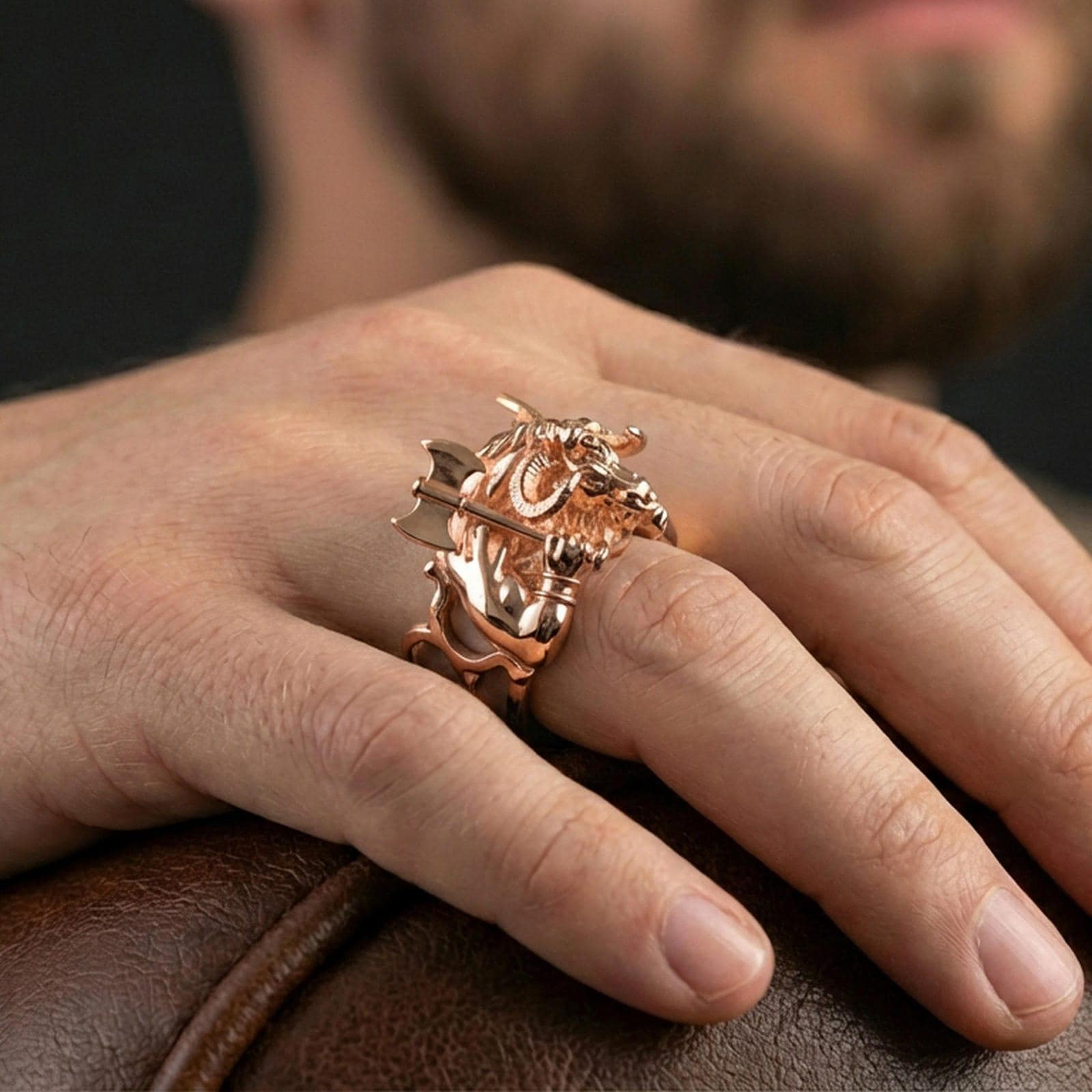 Rose gold plated Minotaur ring on finger featuring sculpted bull-headed warrior with axe, powerful fantasy jewelry lifestyle wear shot