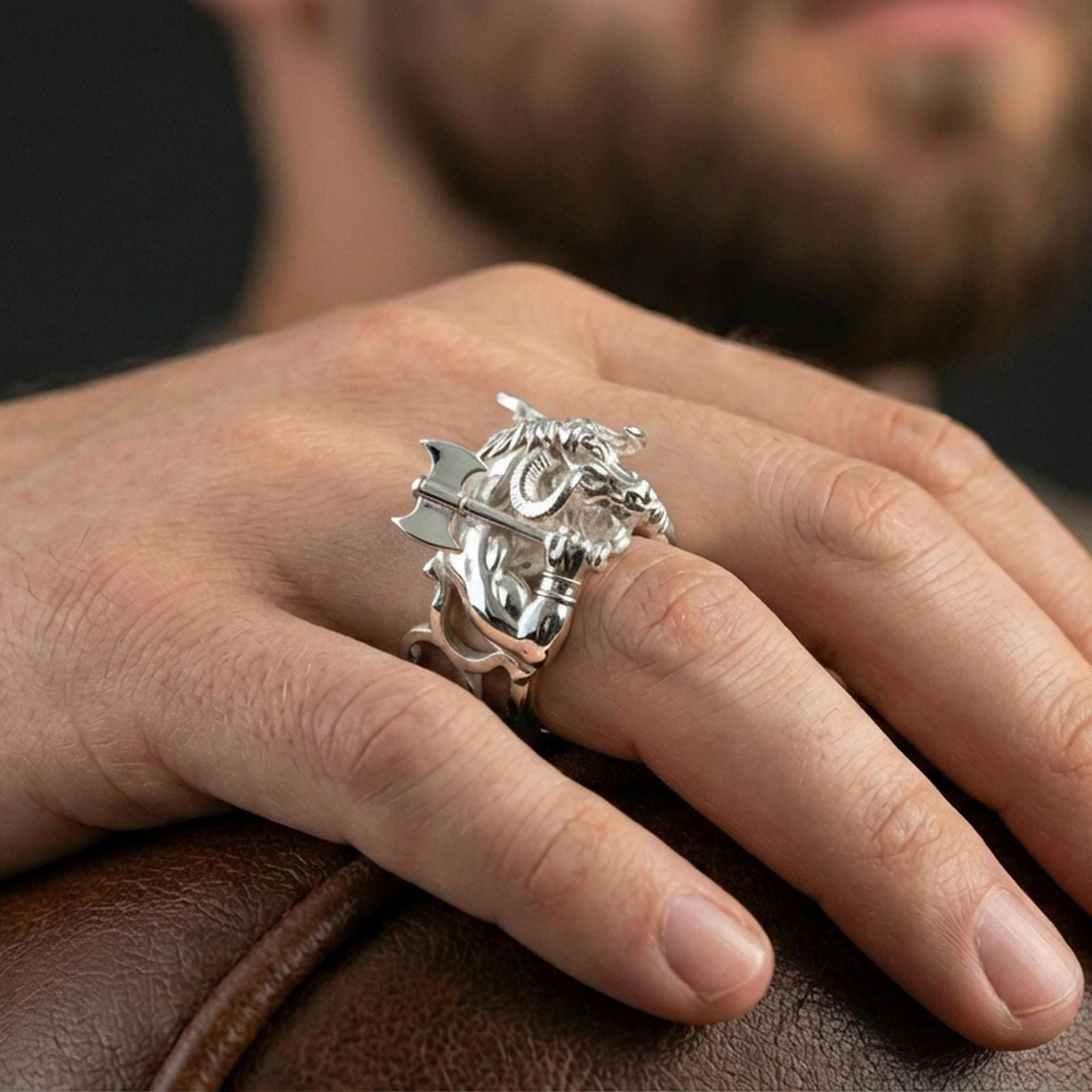 Polished silver Minotaur ring on finger highlighting detailed muscular body and double axe relief, clean lifestyle wear photo