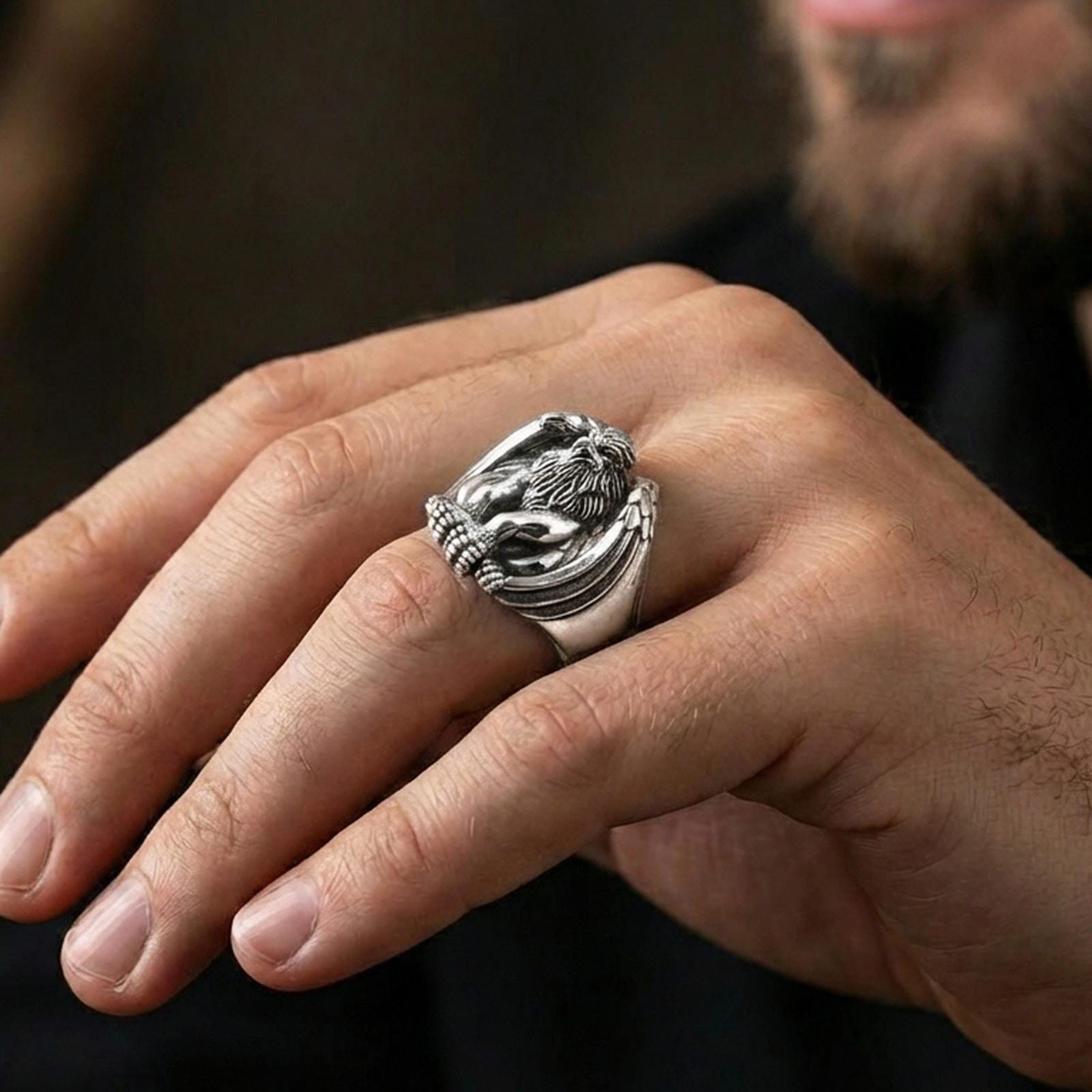 Polished silver griffin signet ring on finger highlighting detailed wings and lion paws, clean lifestyle wear photo