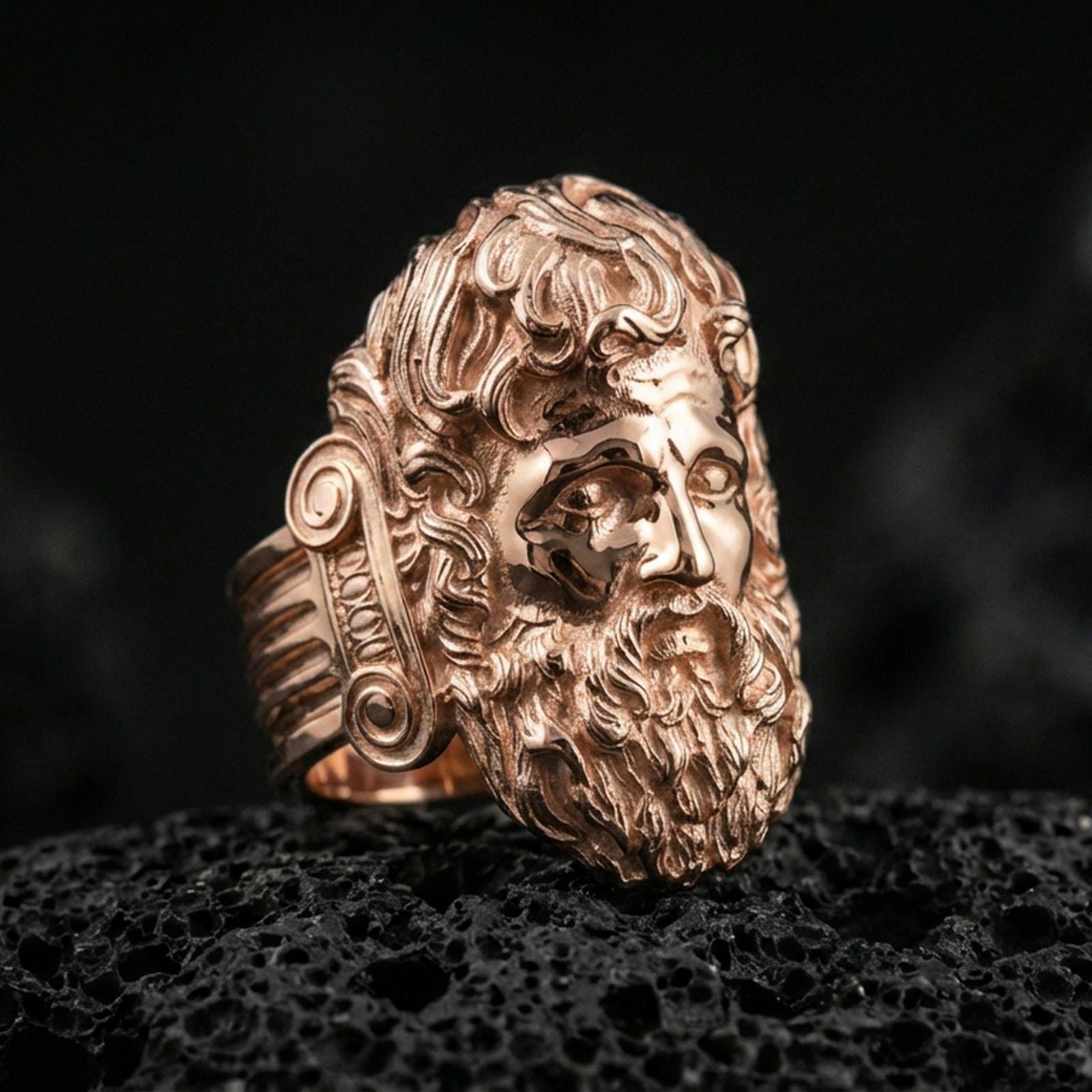 Rose gold plated Zeus ring showcasing expressive god face sculpture and rich texture, sharp close-up product photography on volcanic rock