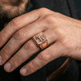 Load image into Gallery viewer, Rose gold plated gryphon signet ring on finger featuring winged beast emblem and framed signet face, refined fantasy jewelry lifestyle wear shot
