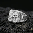 Load image into Gallery viewer, Polished silver gryphon ring featuring raised mythological beast relief and framed square signet design, centered close-up on dark porous volcanic stone
