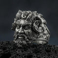 Load image into Gallery viewer, Detailed Czernobog ring crafted in oxidized sterling silver, Slavic dark deity face with horned crown and flowing beard, macro product shot on textured volcanic rock background
