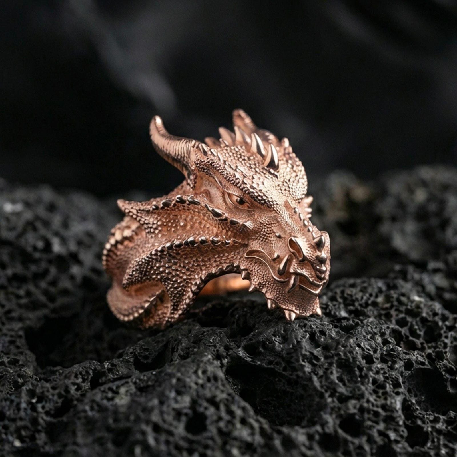 Rose gold plated dragon ring showcasing detailed scale engraving and sharp horned dragon features, crisp close-up product photography on volcanic rock