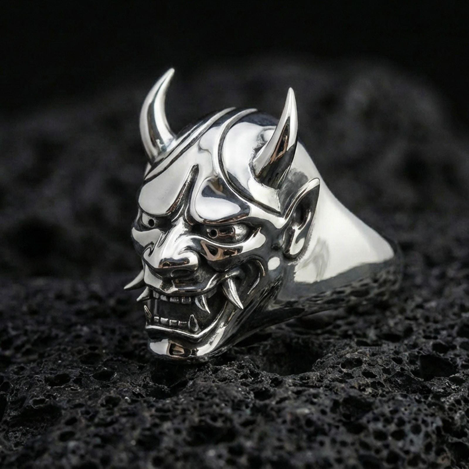 Polished sterling silver Oni mask signet ring on black volcanic stone, detailed menacing Hannya/Oni face, sharp teeth and horned helmet
