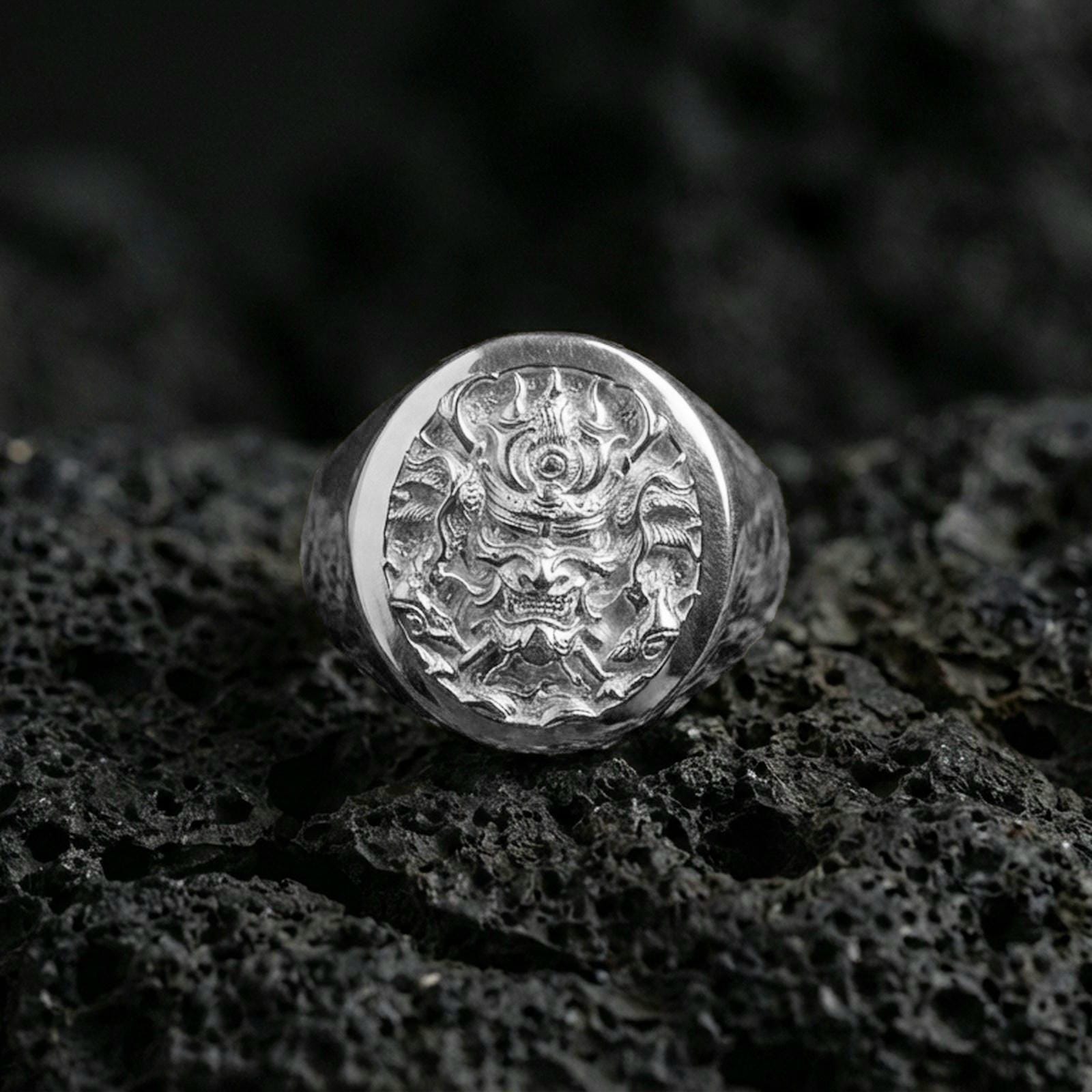 Polished sterling silver samurai warrior signet ring on black volcanic stone, finely engraved samurai face, traditional Japanese armor details