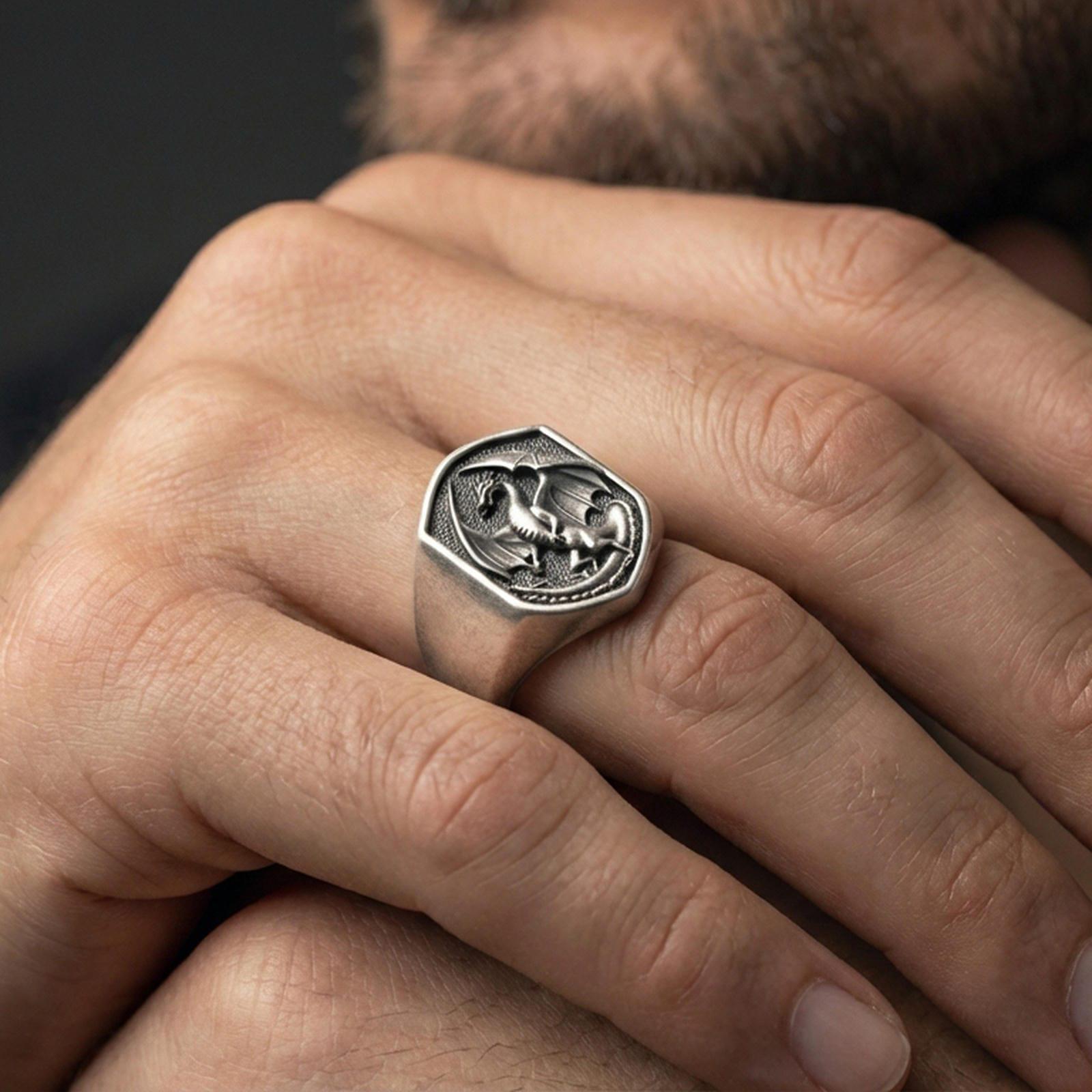 Oxidized sterling silver dragon ring on a human finger, winged dragon relief, dark fantasy gothic styling