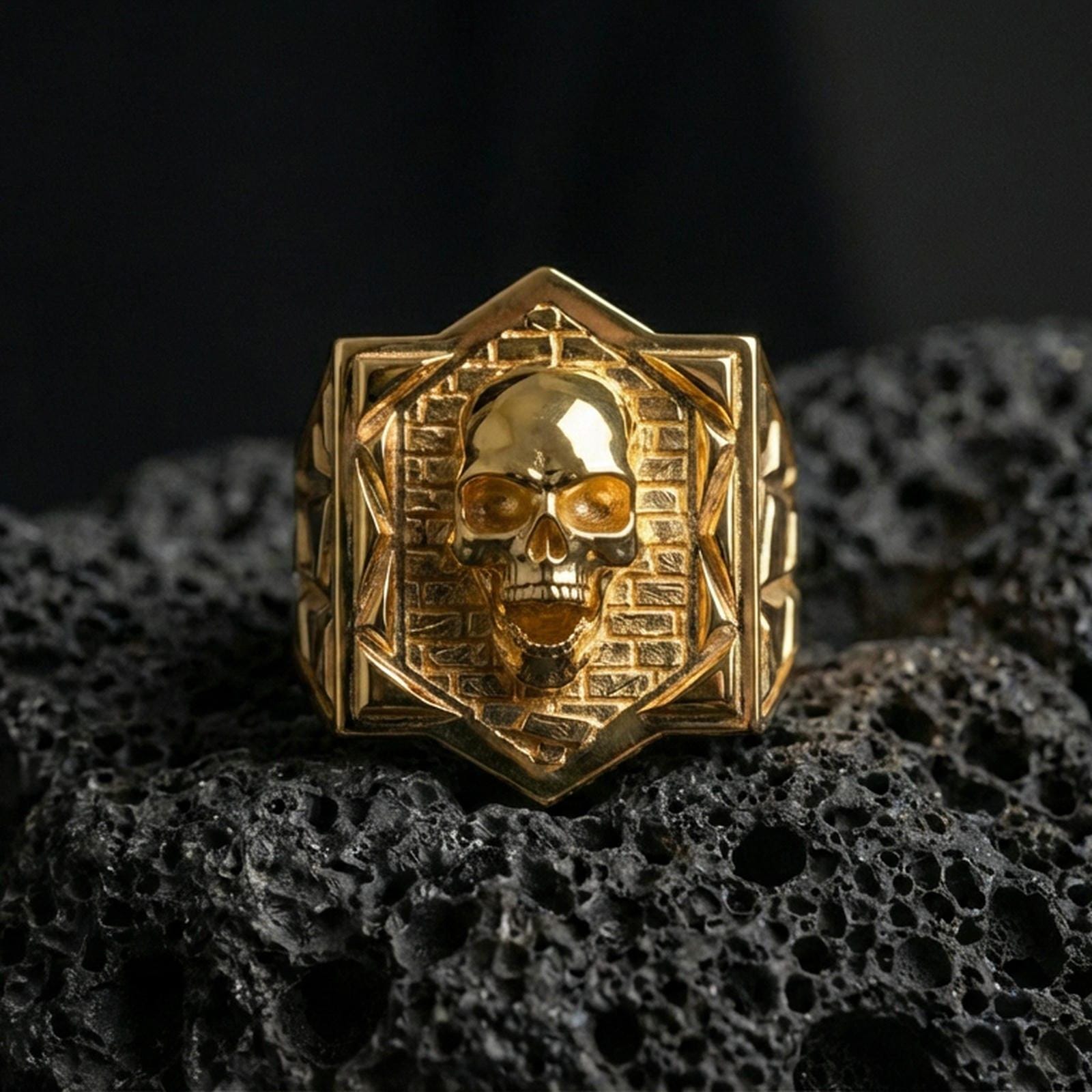 Gold plated skull signet ring on black volcanic stone, gothic brickwork design, bold men’s ring