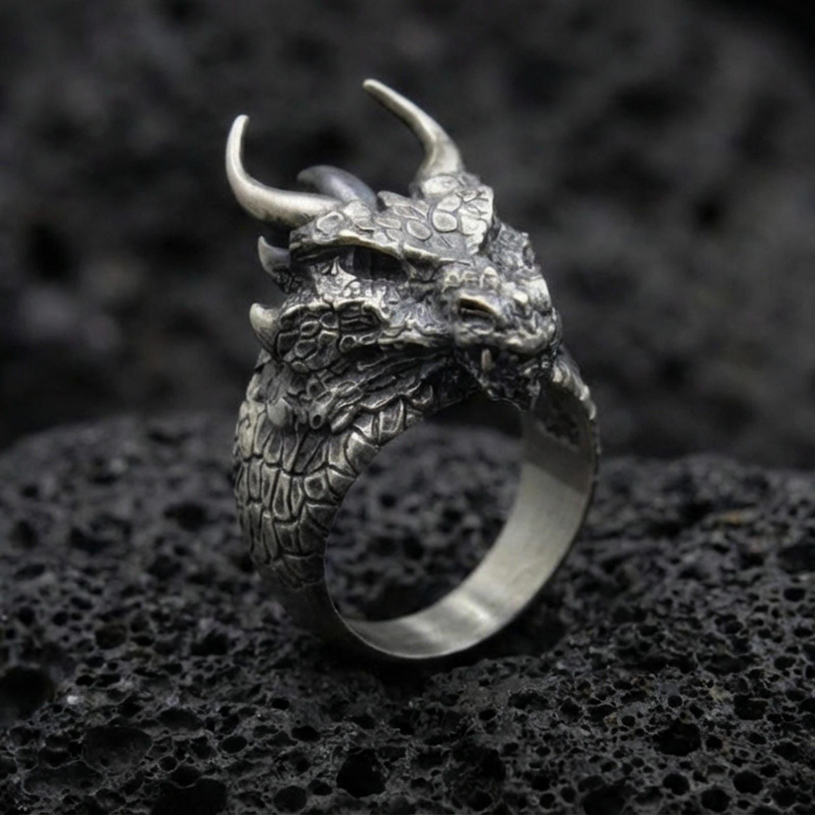 Oxidized sterling silver horned dragon ring on black volcanic stone, detailed dragon head and scales, mythical creature jewelry