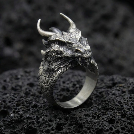 Oxidized sterling silver horned dragon ring on black volcanic stone, detailed dragon head and scales, mythical creature jewelry