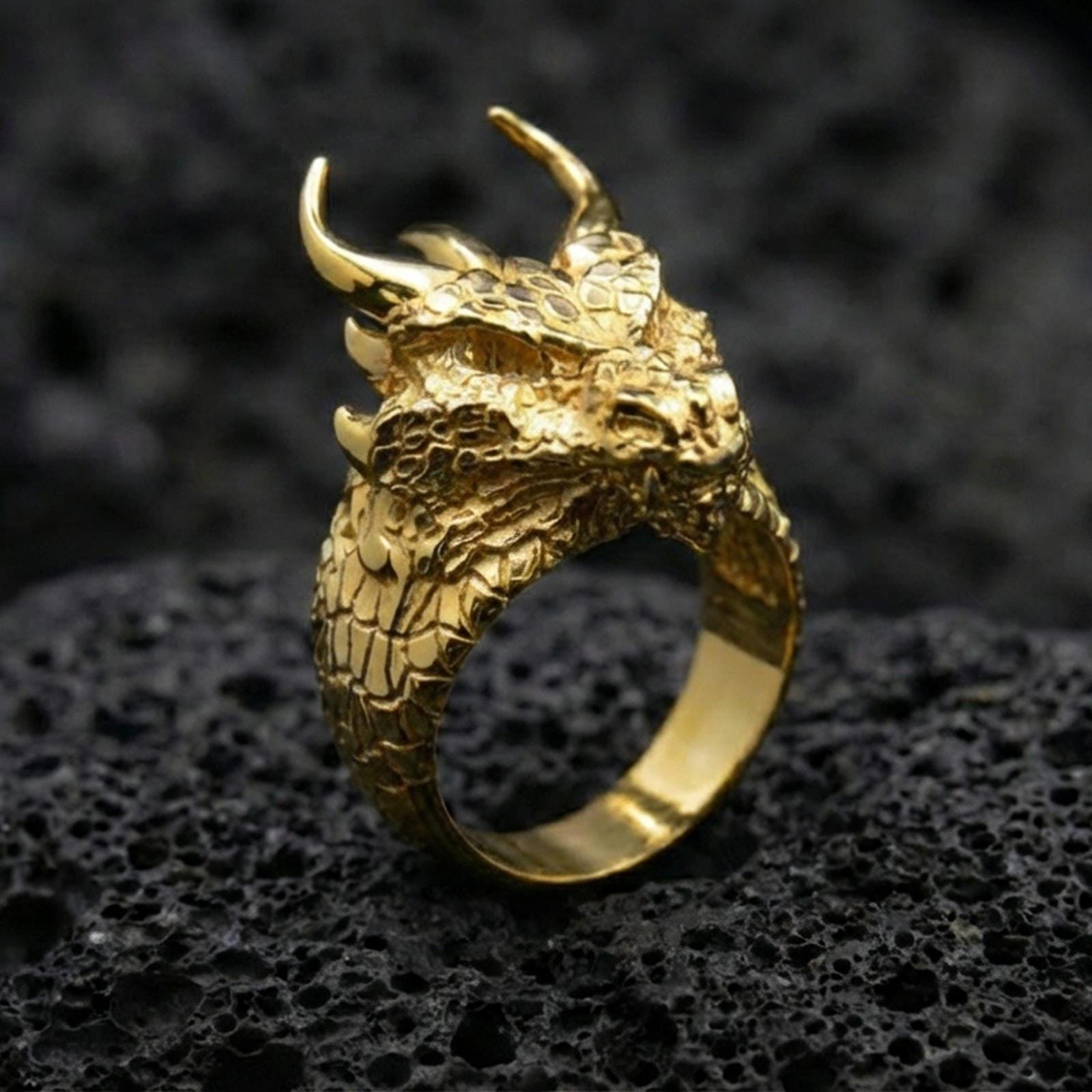 Gold plated horned dragon ring on black volcanic stone, intricate dragon scales and horns, bold mythic jewelry