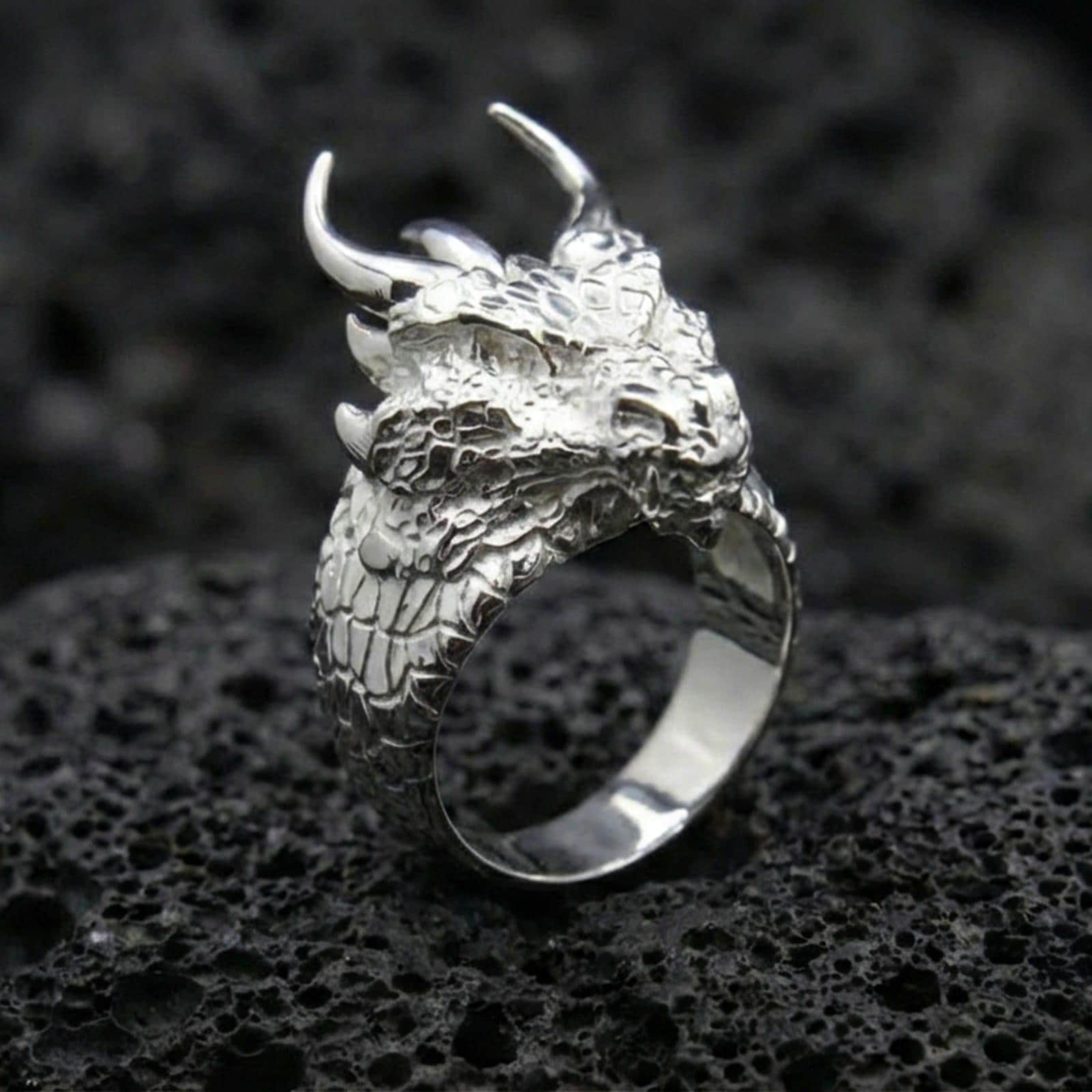 Polished sterling silver horned dragon ring on black volcanic stone, sculpted dragon head with horns, fantasy statement ring