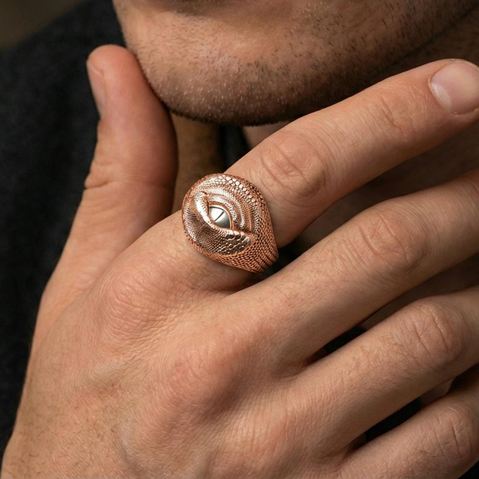Rose gold plated dragon eye ring on a human finger, dragon scale texture with eye detail, dark fantasy accessory