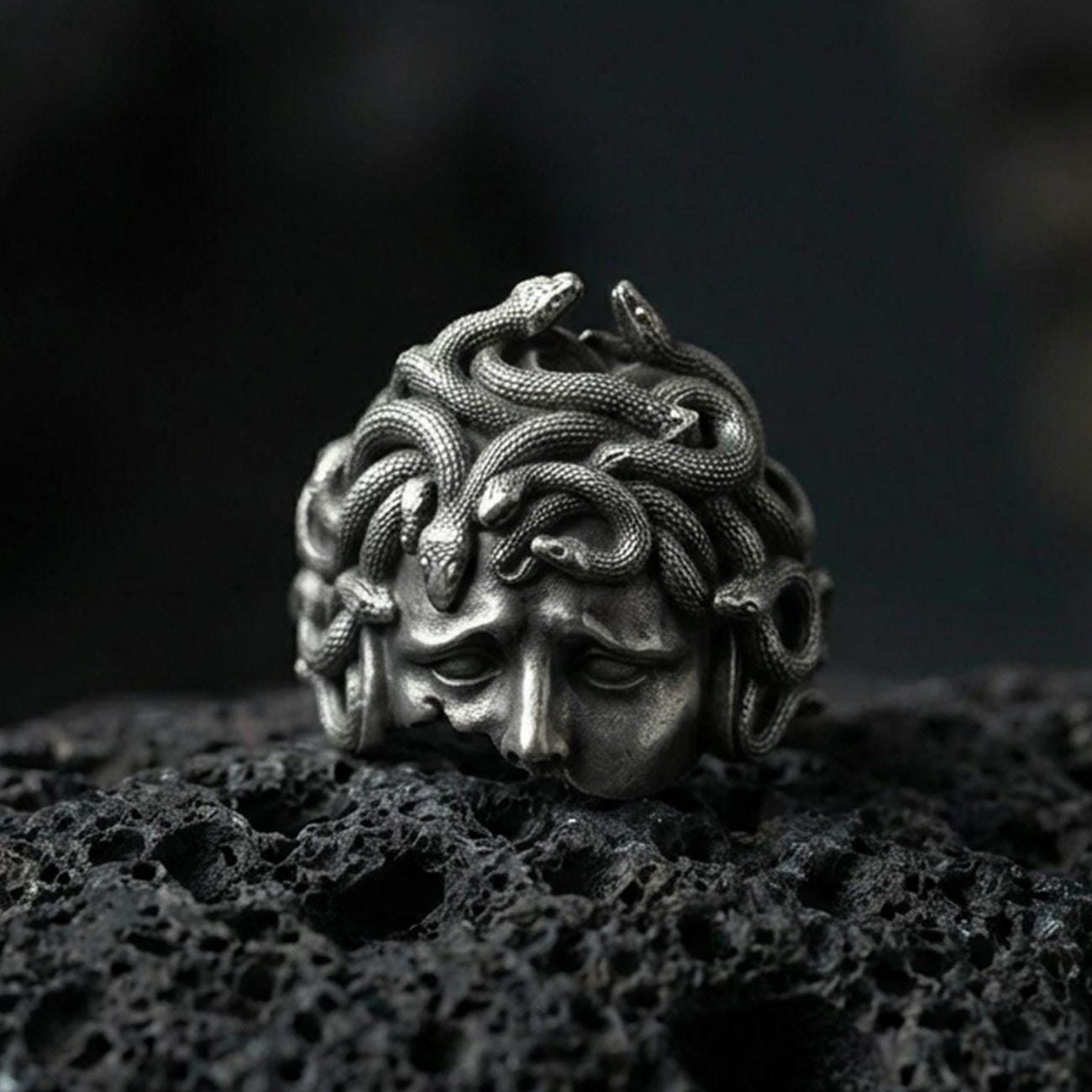 Oxidized sterling silver Medusa head ring on black volcanic stone, snake hair gorgon face relief, Greek mythology signet ring