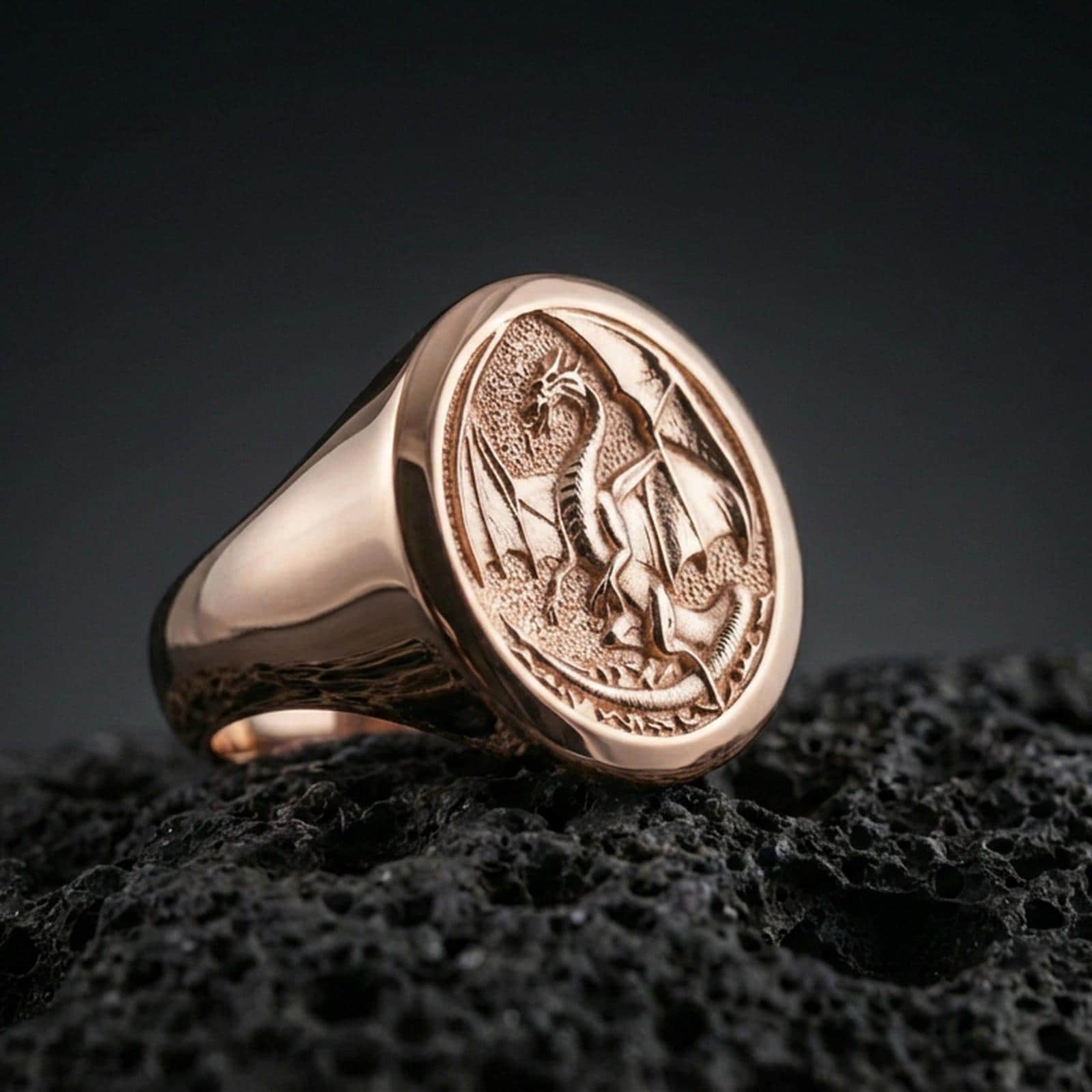 Rose gold plated dragon signet ring on black volcanic stone, detailed dragon carving, symbolic medieval jewelry