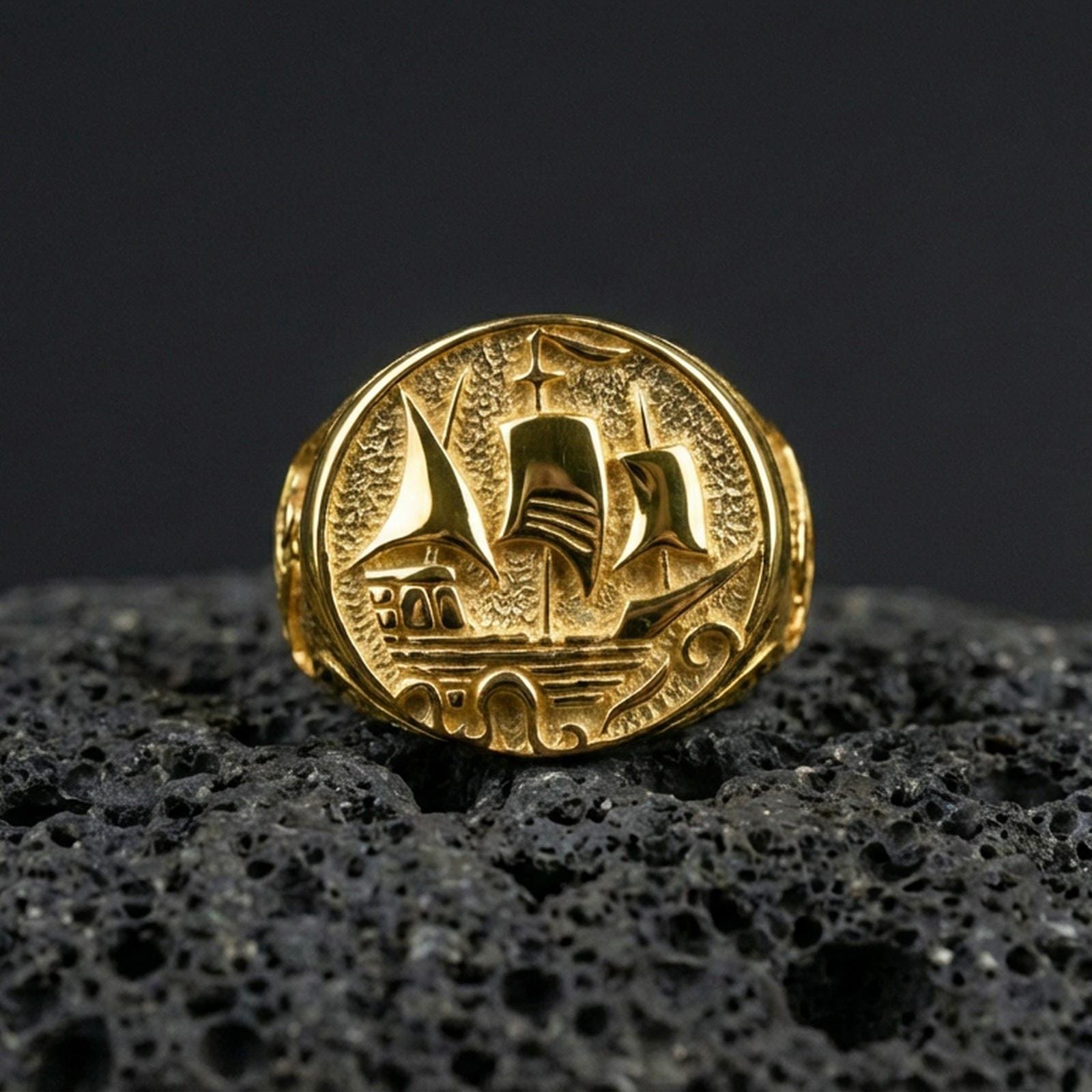 Gold plated Flying Dutchman ship signet ring on black volcanic stone, raised sailboat motif, maritime pirate ring