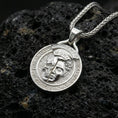 Load image into Gallery viewer, Polished silver memento mori medallion necklace on dark volcanic rock, Latin border engraving detail, premium close-up
