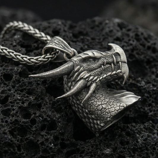 Oxidized sterling silver dragon pendant on textured volcanic rock, detailed scale pattern and horns, macro studio shot