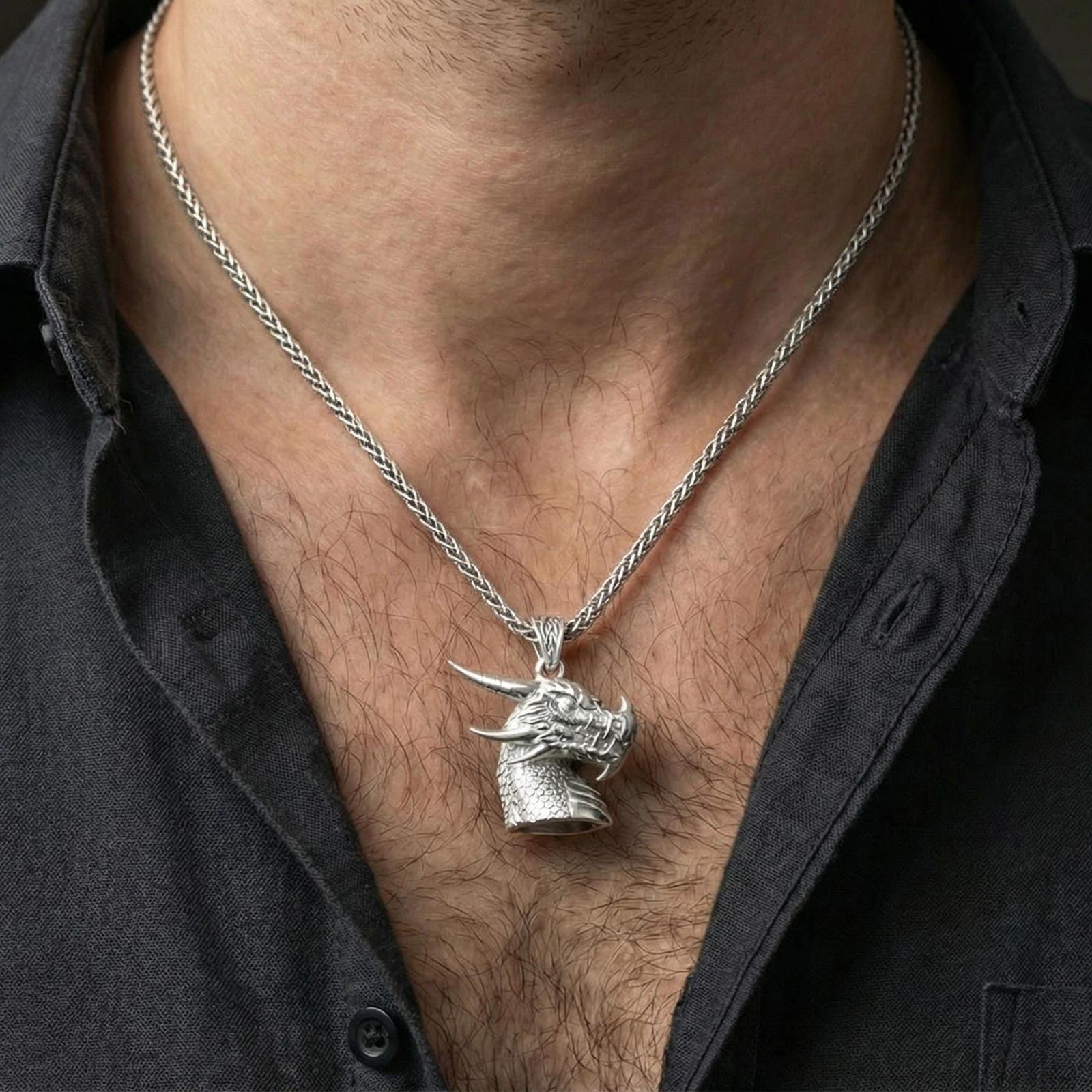 Polished silver dragon head pendant necklace worn on neck, close lifestyle crop, clear scale texture and horn details