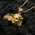 Load image into Gallery viewer, Gold plated Hypnos pendant on porous volcanic rock backdrop, Greek god of sleep face design with wing accent, high-contrast lighting
