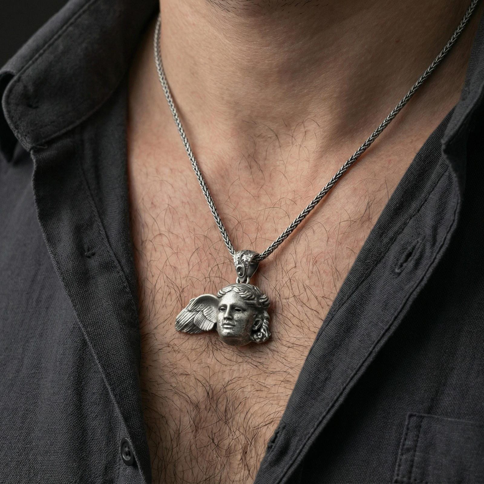 Oxidized sterling silver Hypnos pendant worn on neck on a braided chain, centered chest framing, moody lifestyle studio shot